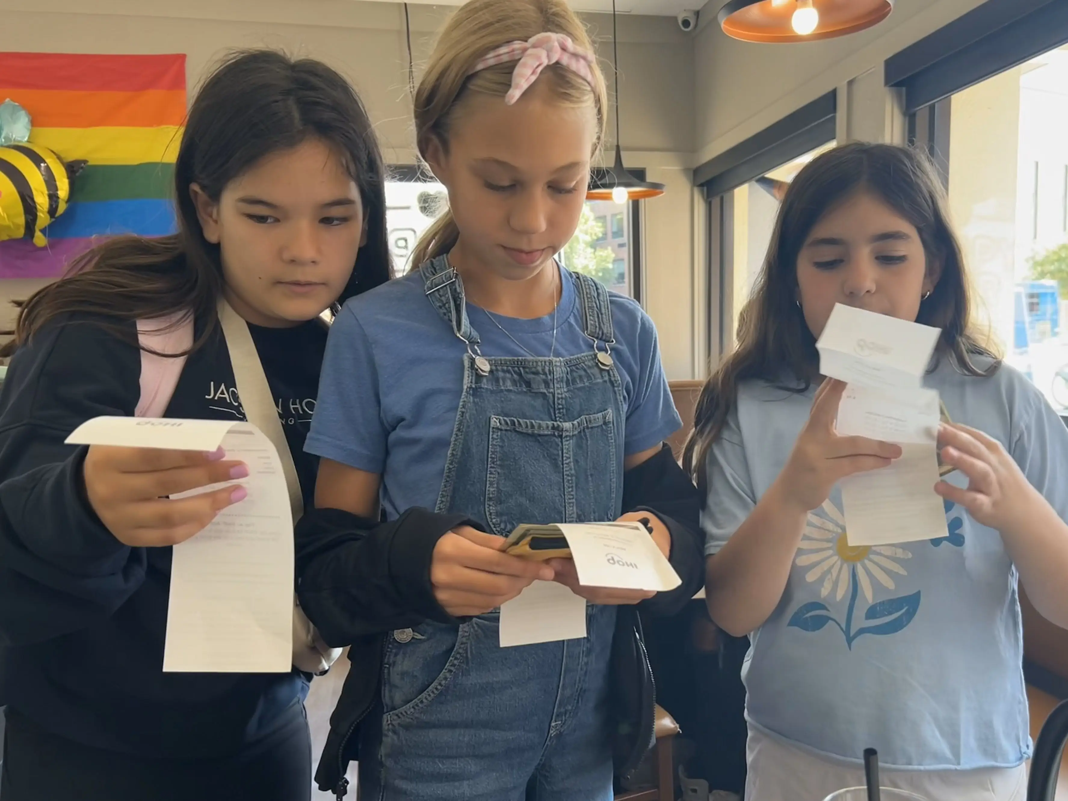Three girls holding receipts.