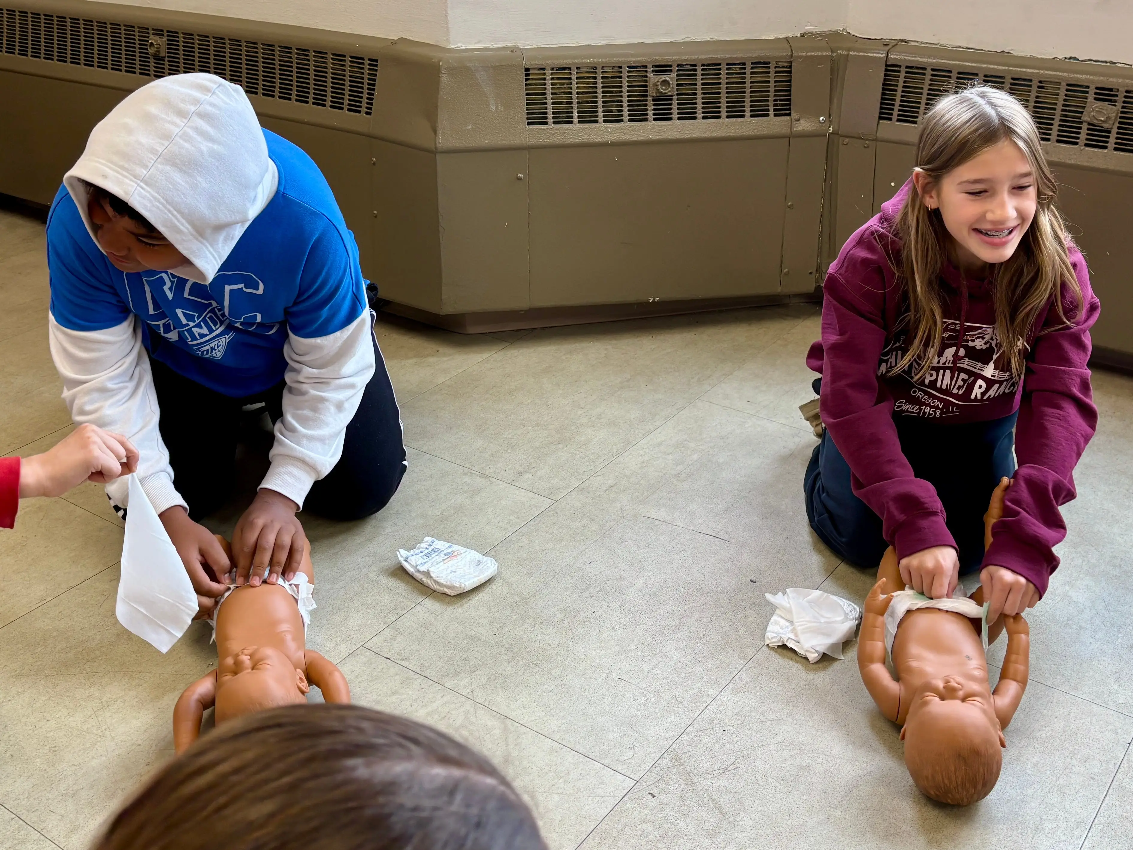 Two kids practicing CPR on baby dolls