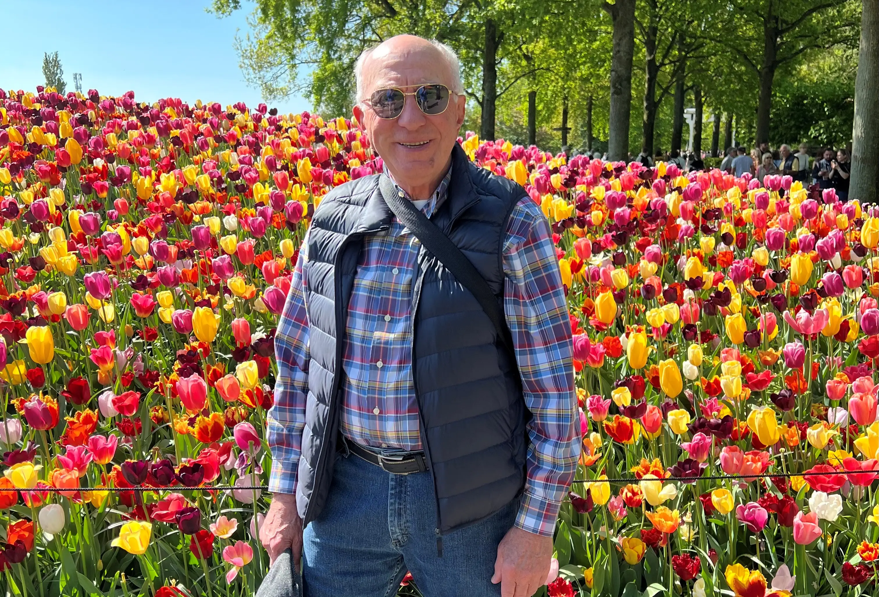an older man poses in front of tulips