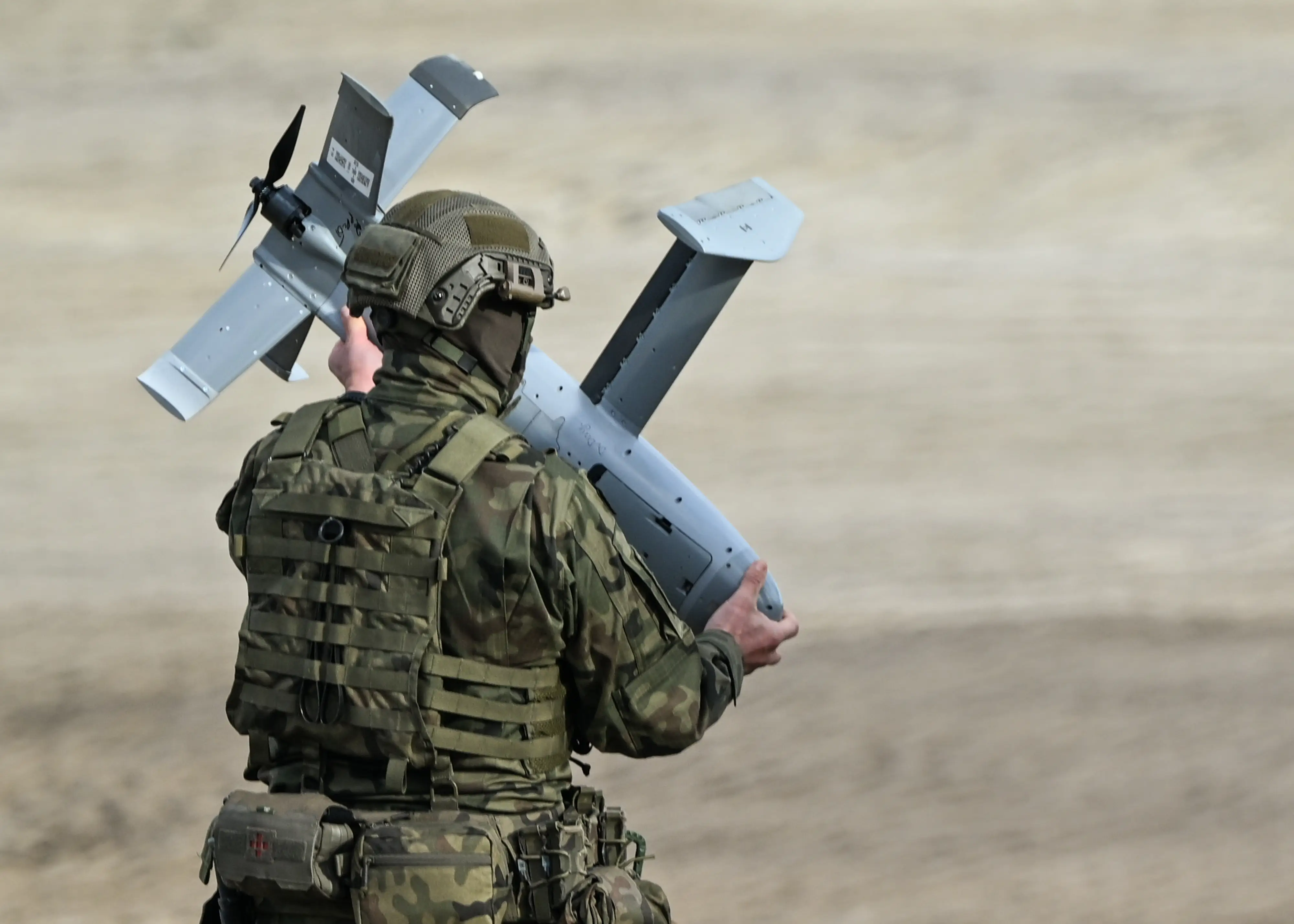 A Polish Army soldier carries an AS3 Surveyor interceptor drone, part of the US counter-drone system known as 'MEROPS,' during a live-fire demonstration at the Deba training grounds in Subcarpathian Voivodeship, Poland, on November 18, 2025.