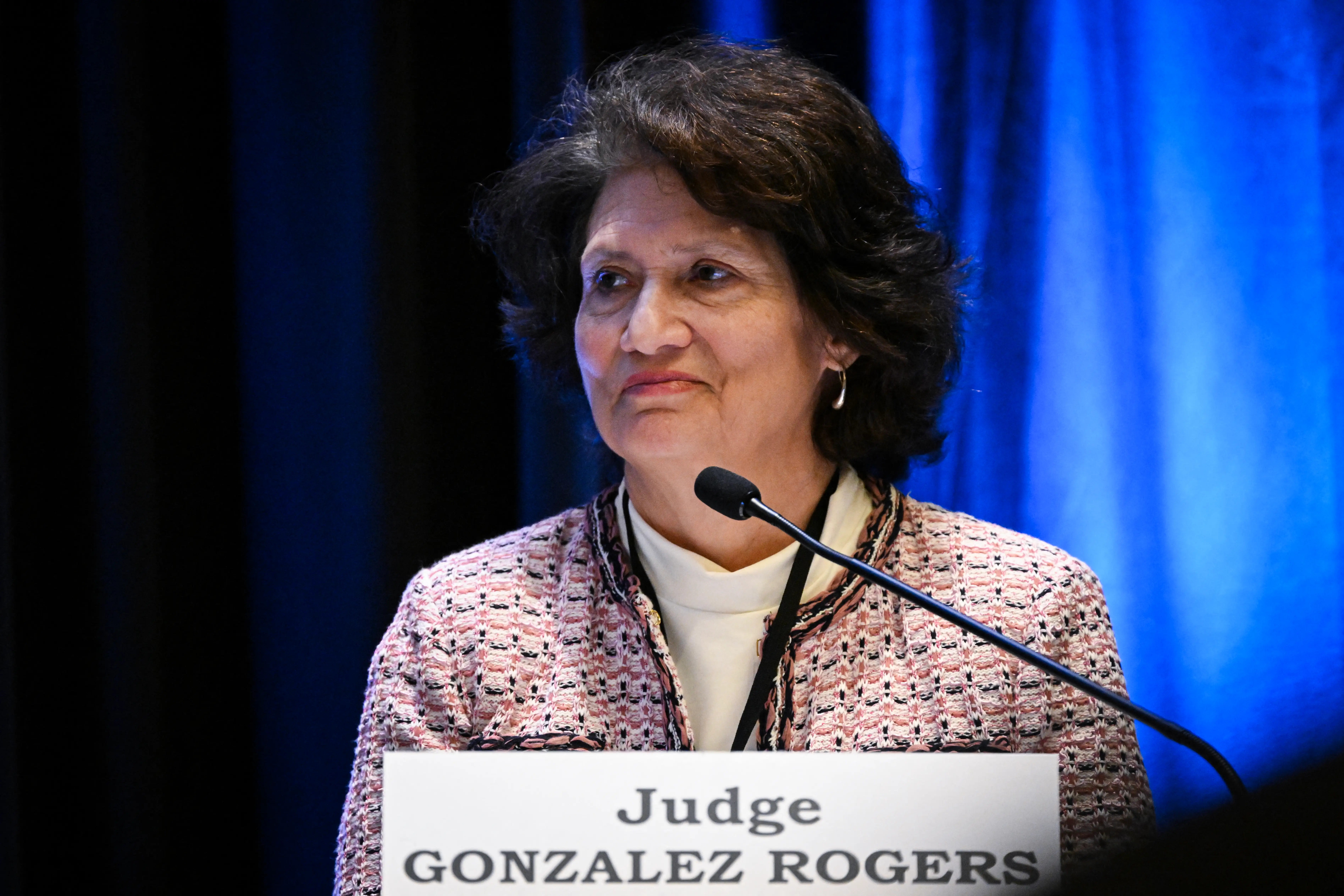 A woman stands before a microphone