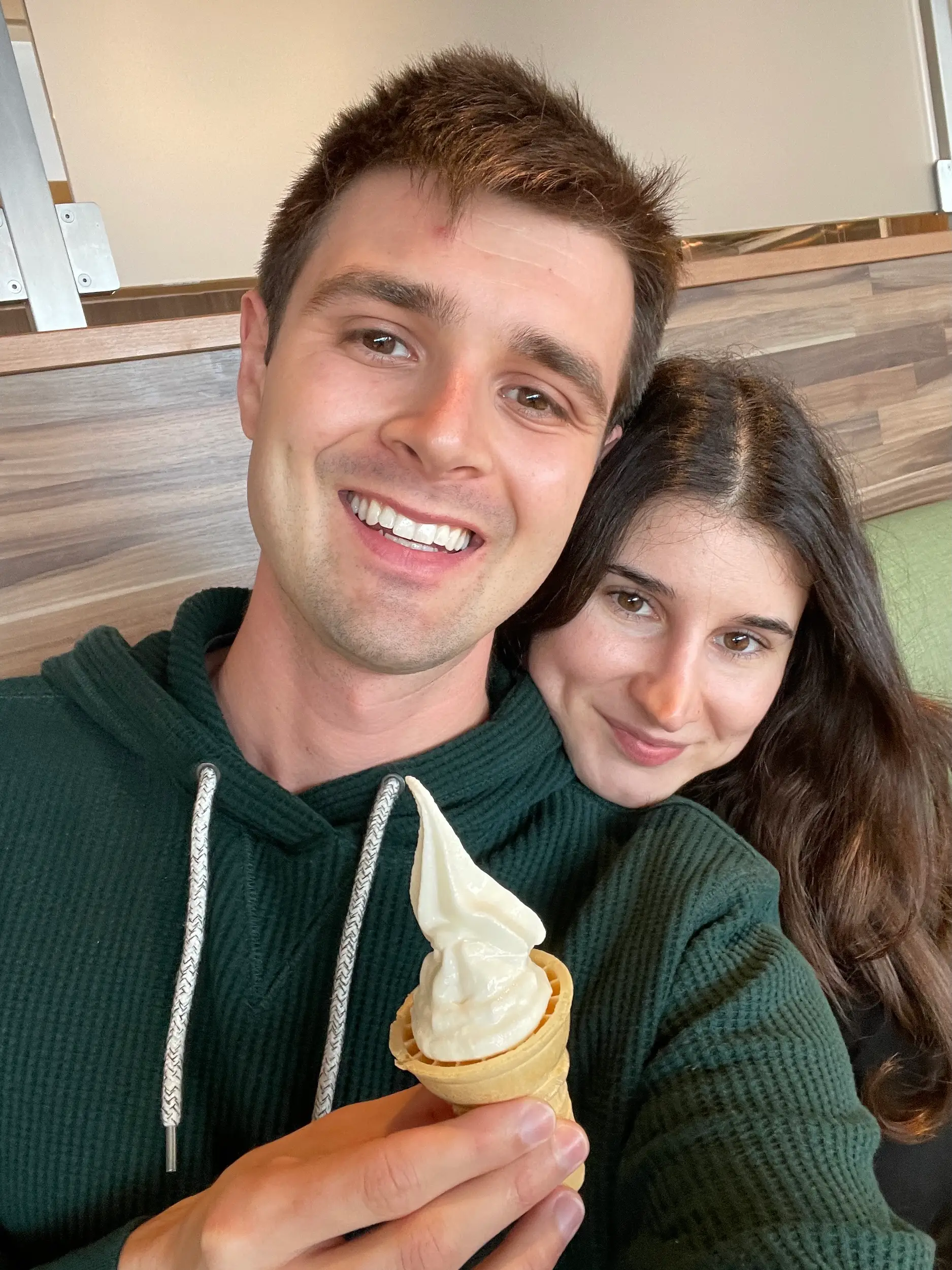 A selfie of a man and woman holding an ice-cream cone.