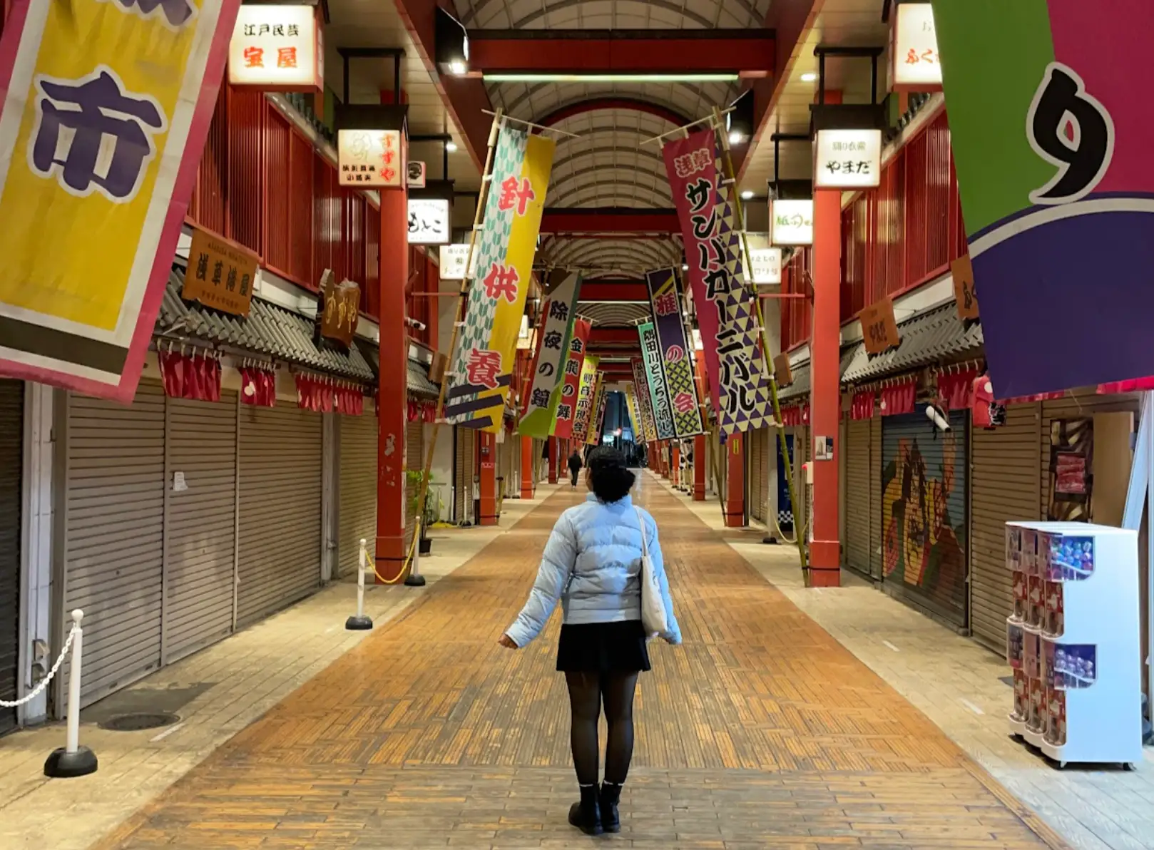 The writer standing in a building in Japan, surrounded by signs and flags.