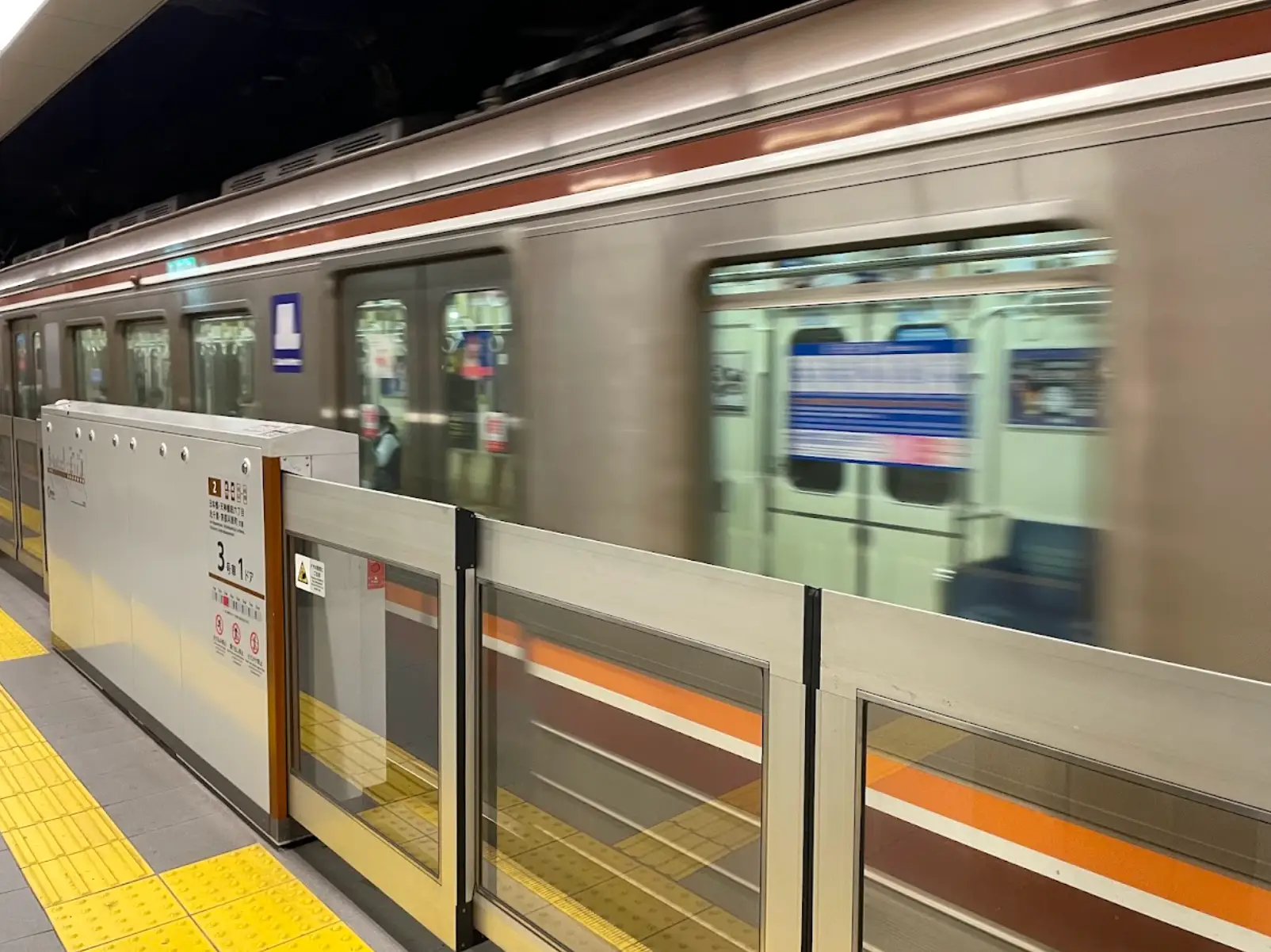 A blurry train moving quickly past a station in Japan.