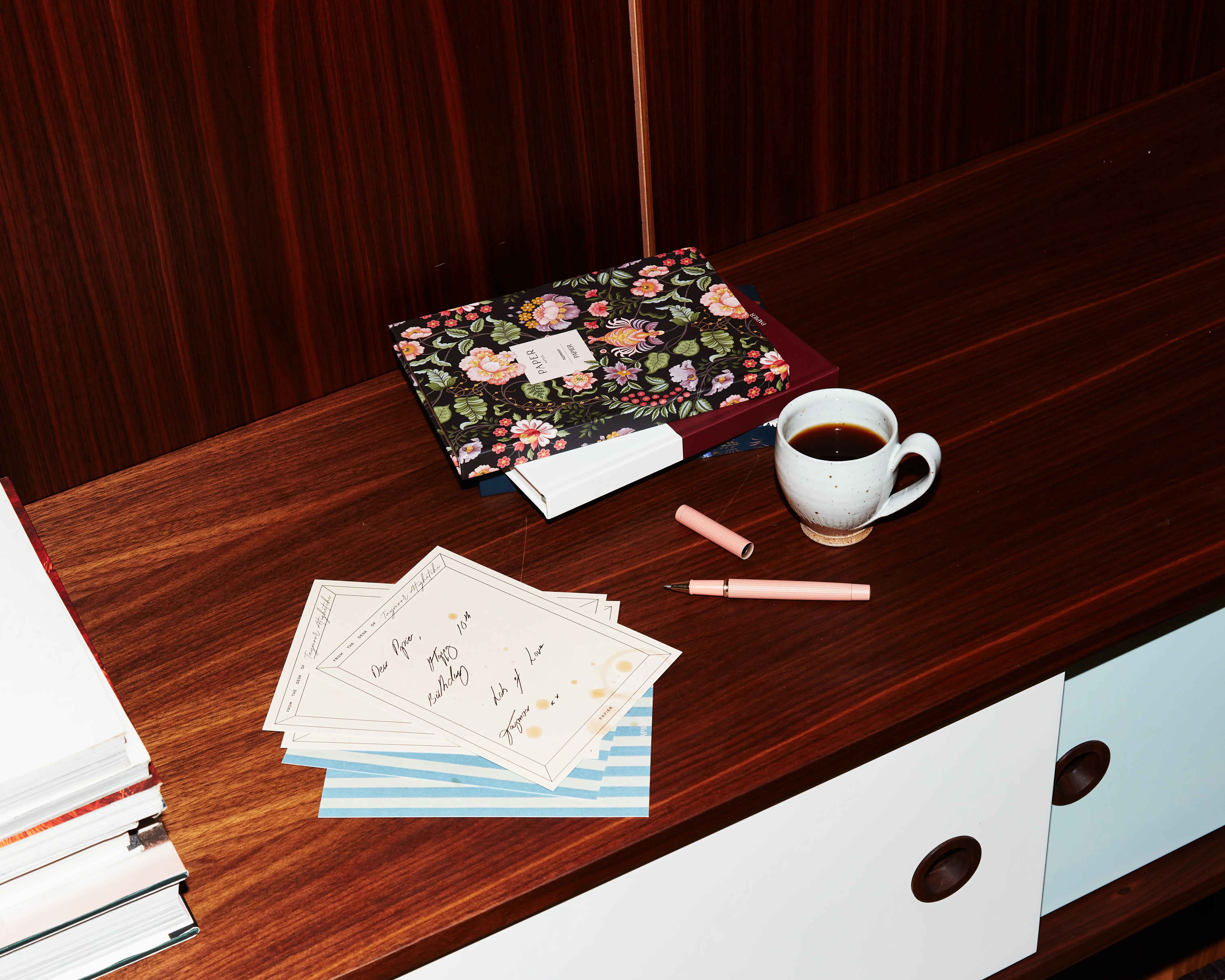 Papier notecard with a happy birthday message, with pens and notebooks beside it.