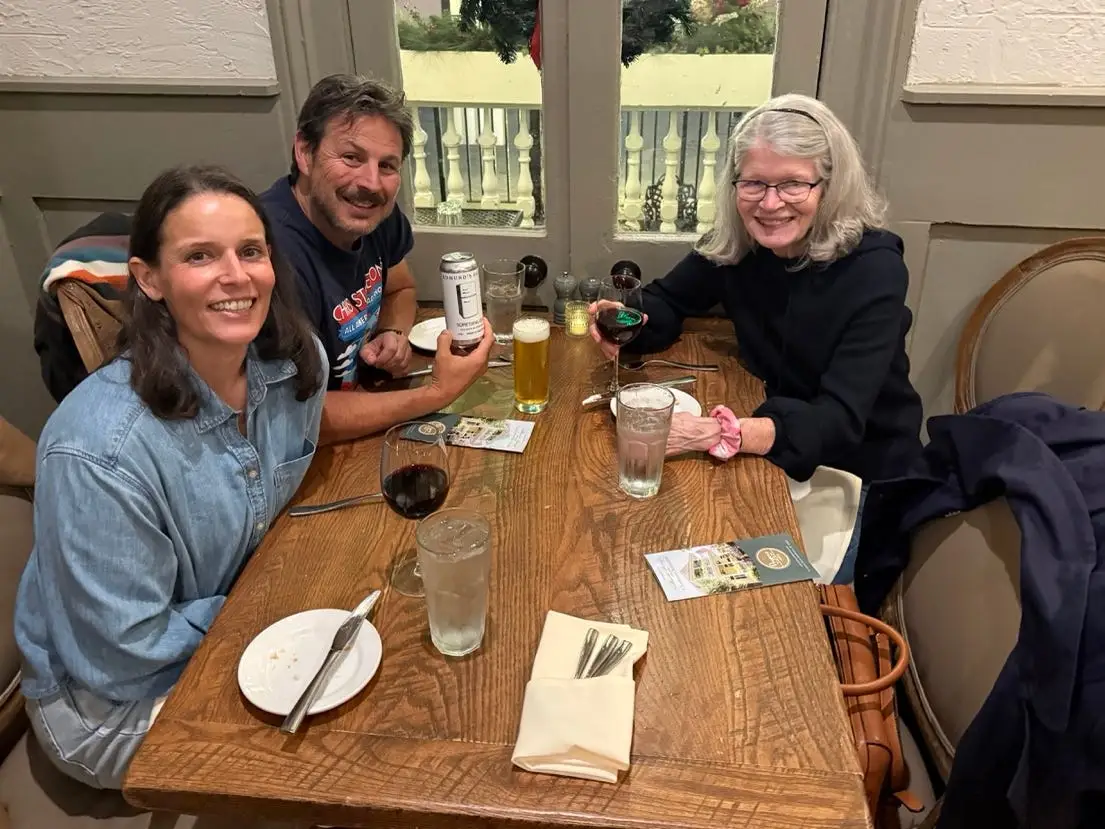 Three people smiling at dinner table