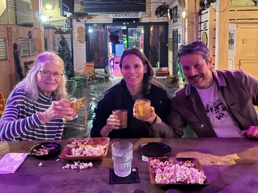 Three people smiling making cocktails
