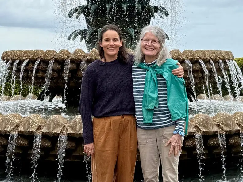 Two women smiling in front of pinrapple fountain