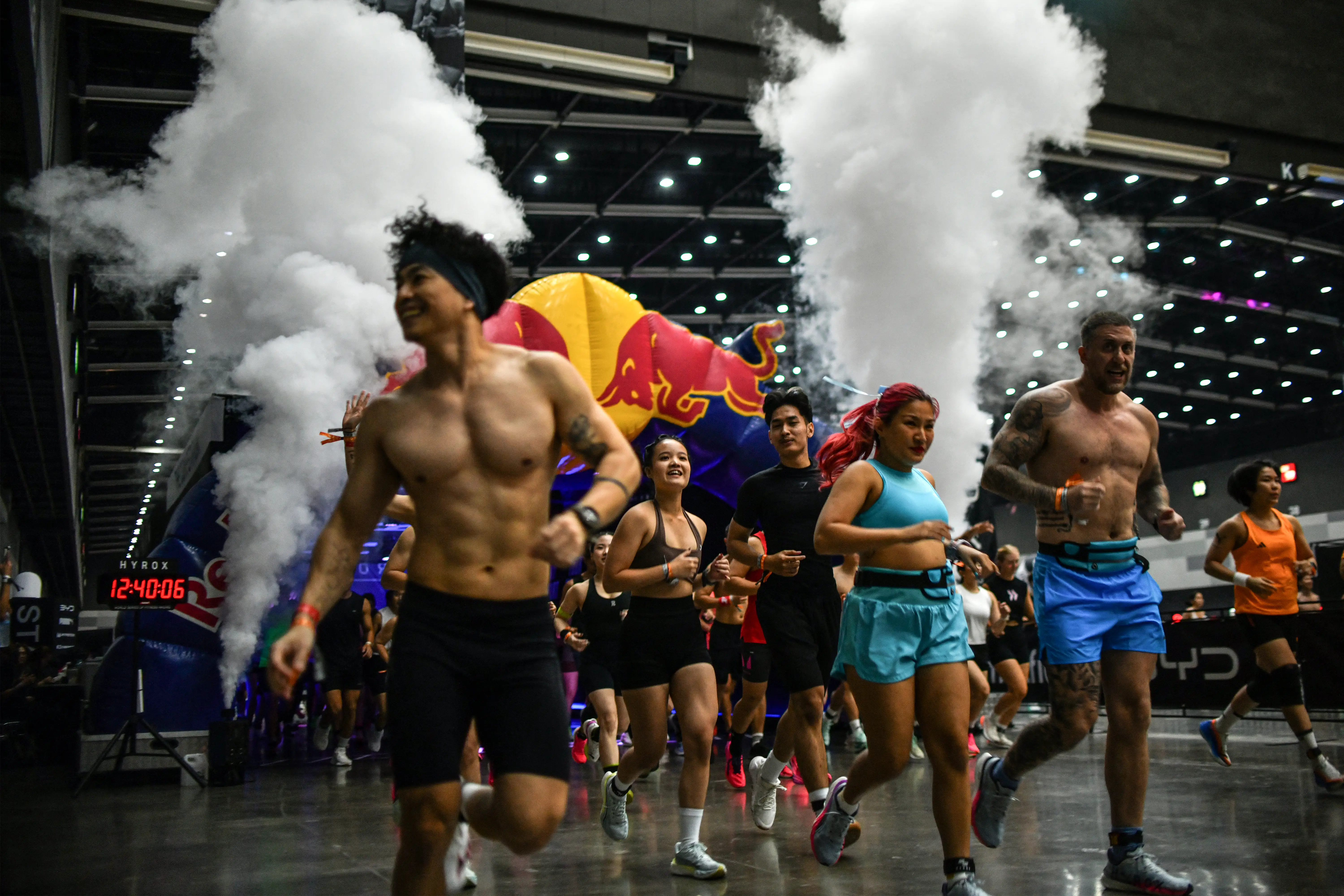 A group of athletes preparing for a Hyrox event with colored lights and a fog machine in the background