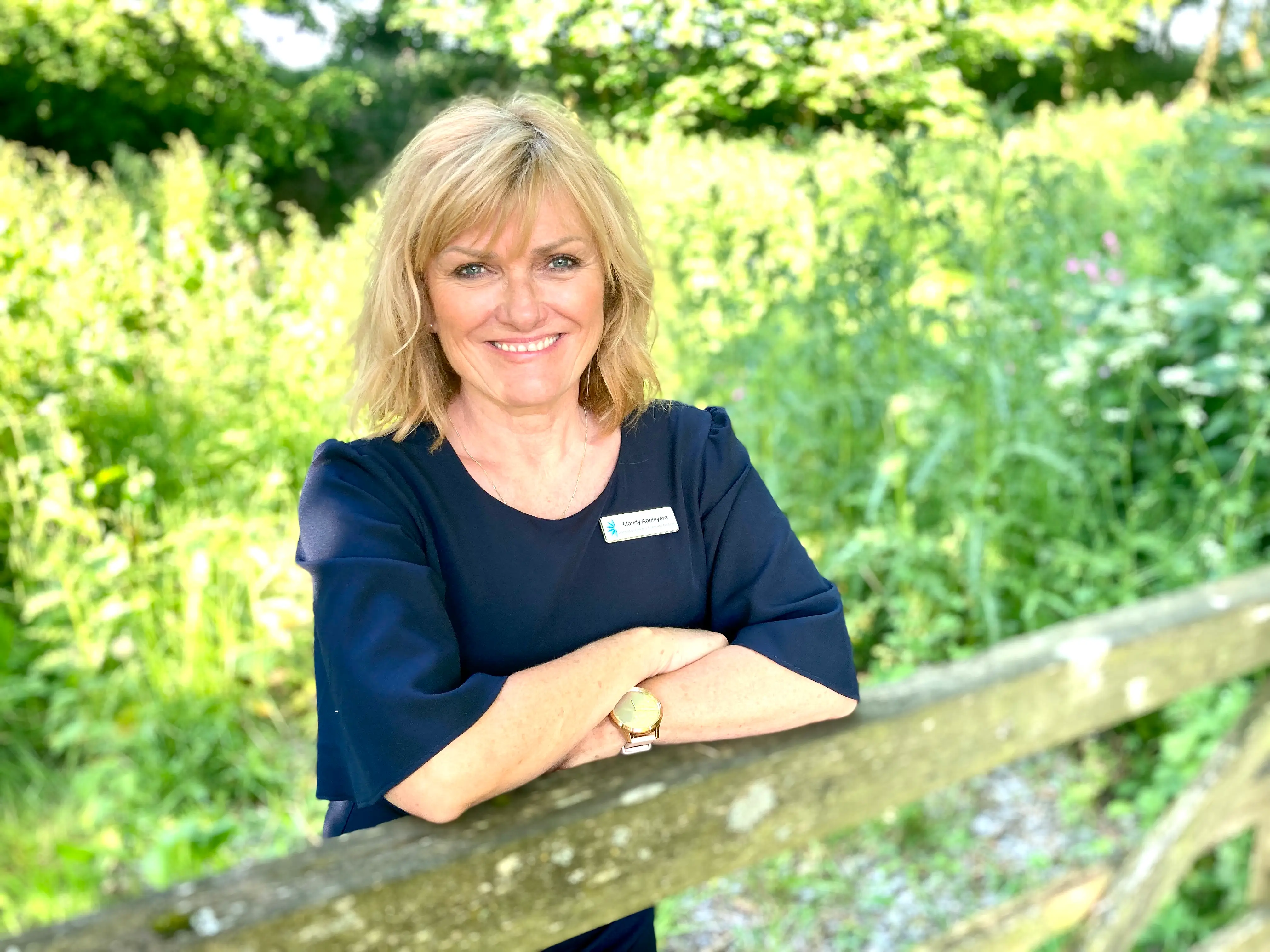 A woman wearing a navy blue dress leaning over a fence.
