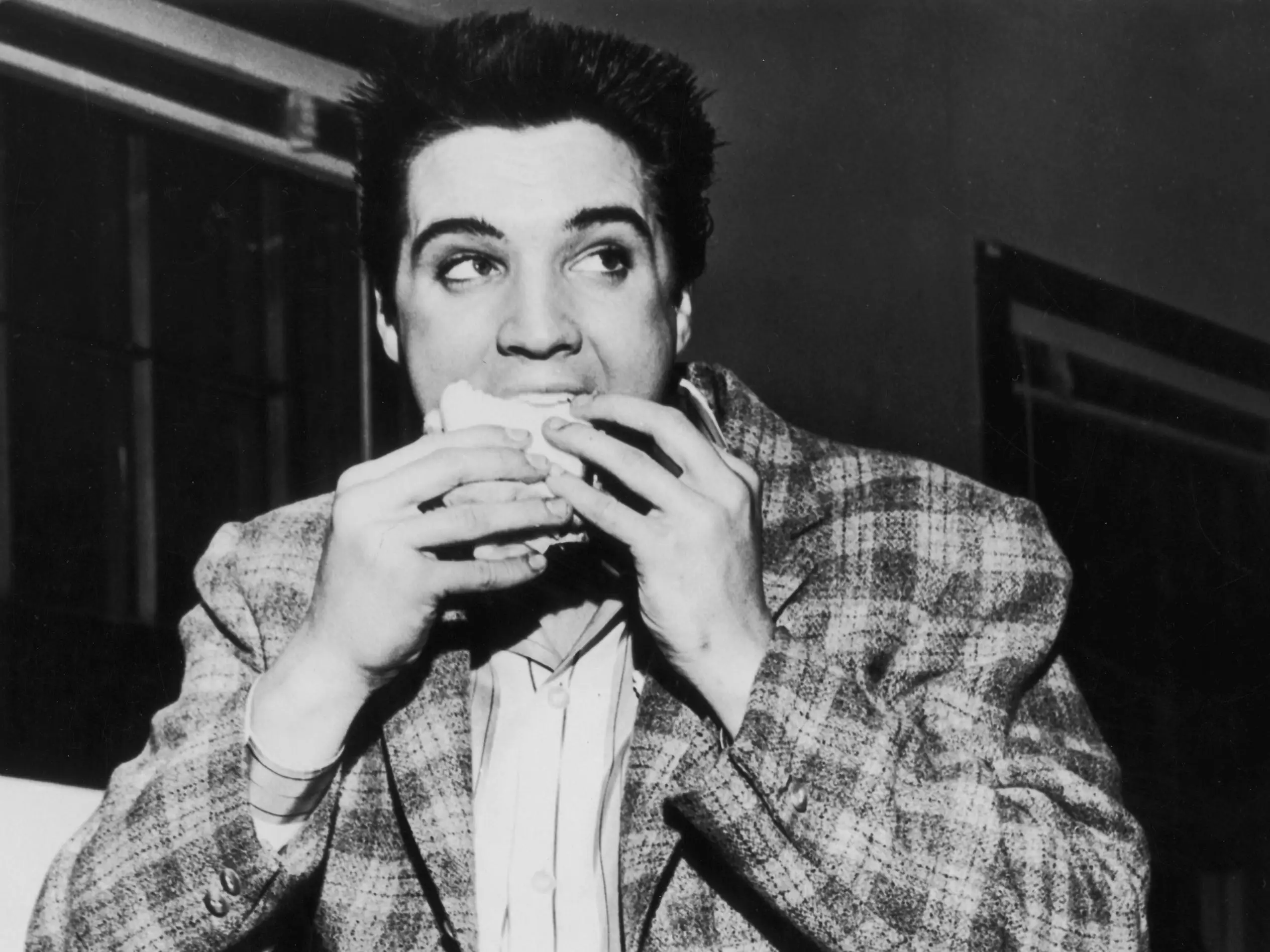 Elvis Presley eating a sandwich.