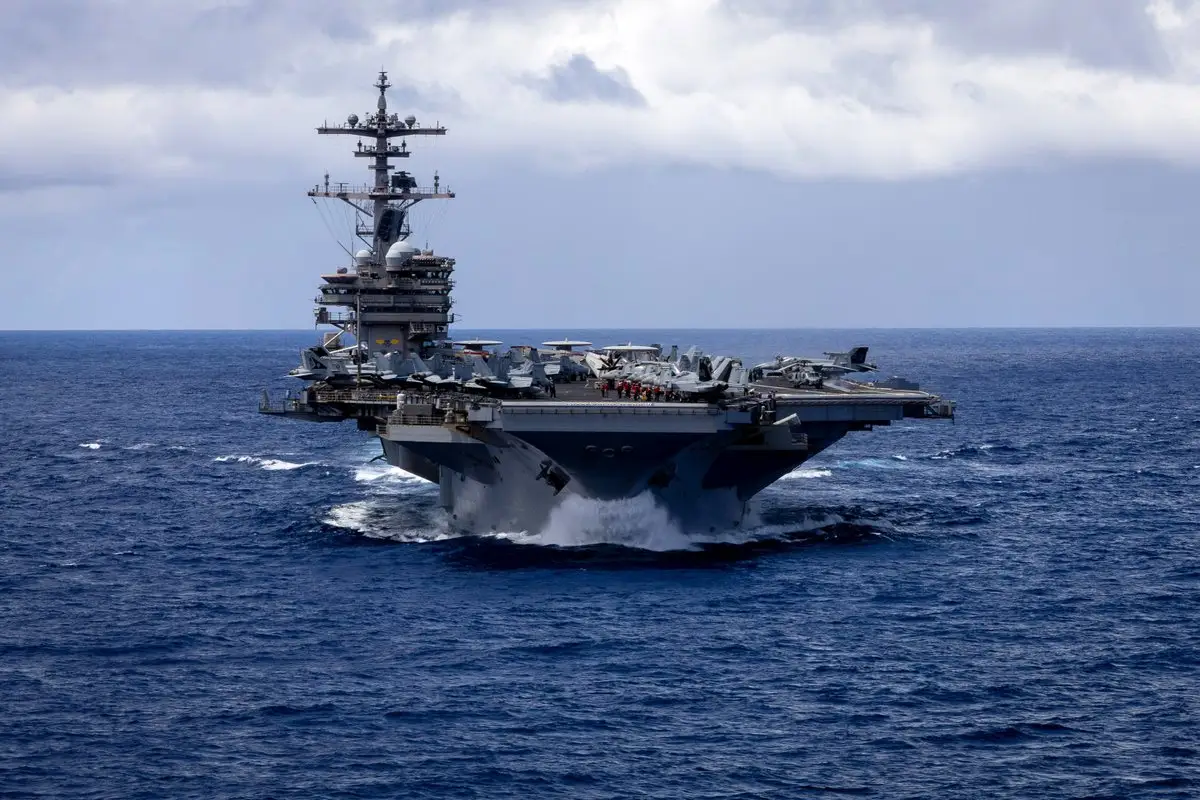 The USS George H.W. Bush aircraft carrier sails in dark blue ocean waters.