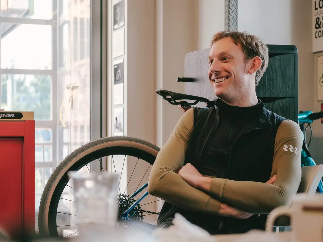 A man sitting his arms crossed with a bicylce in the background.