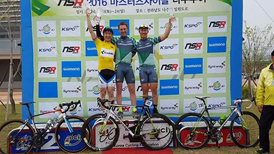 Cyclists standing on a podium with bicyles in front of them.