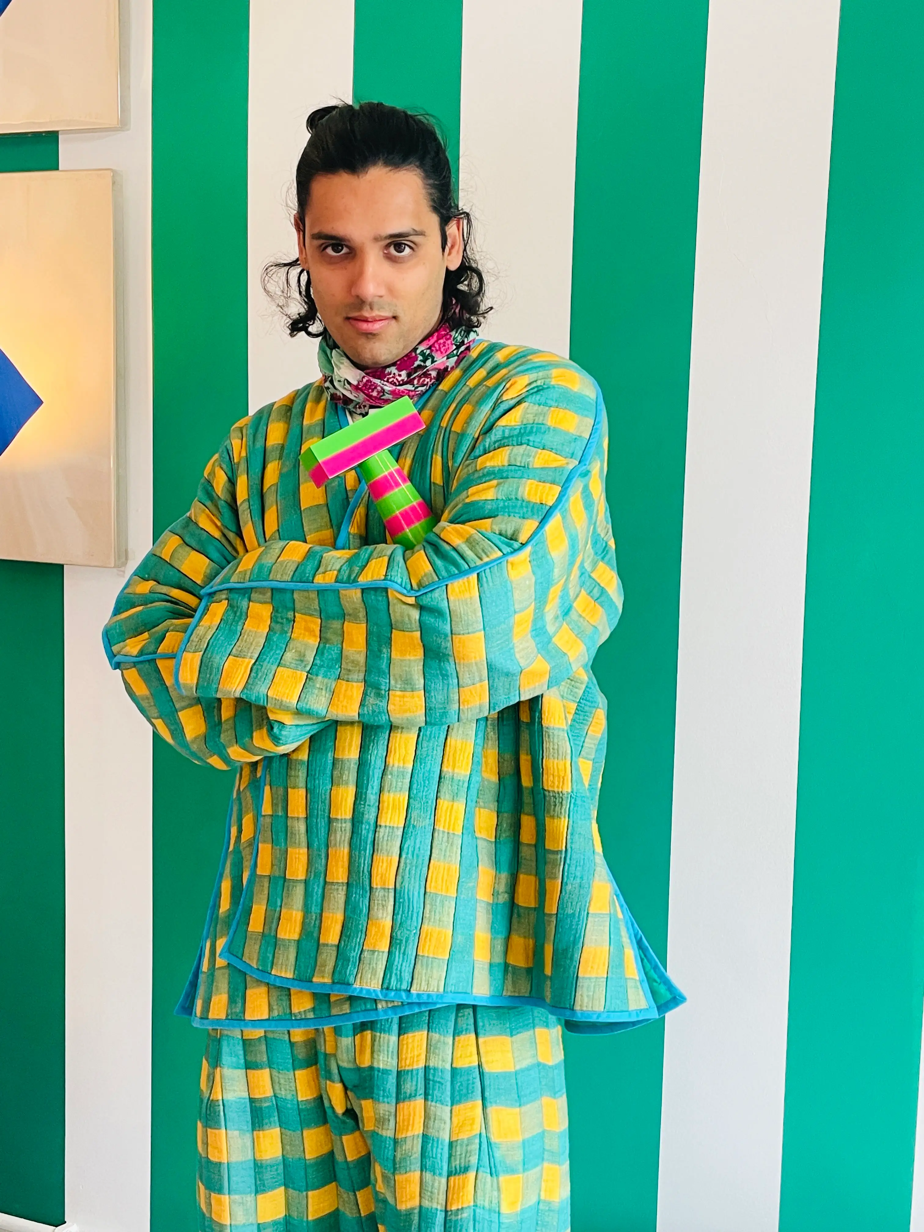 Sachin Raoul poses while wearing a checked yellow, green and blue jacket and top.