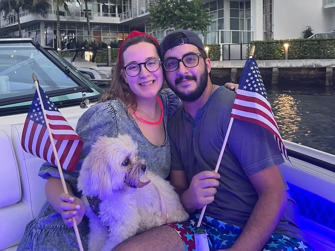 a couple poses with USA flags on a boat in Miami