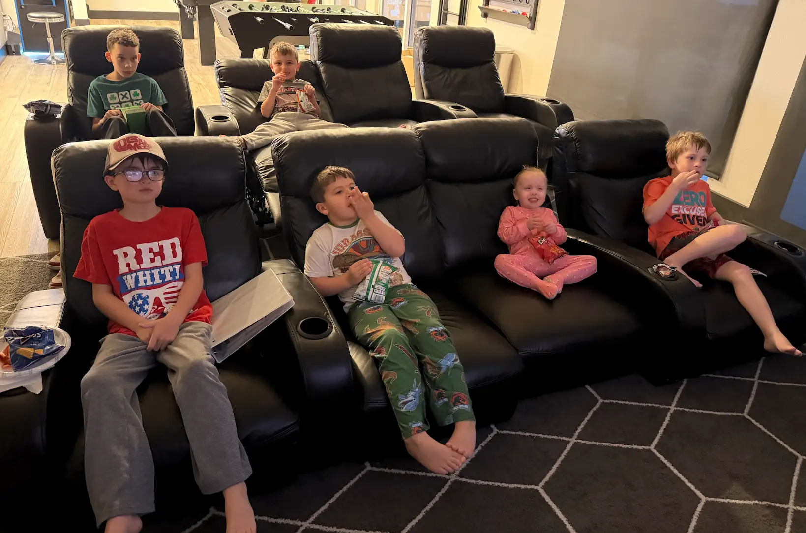 Kids sitting in movie chairs in a cabin.