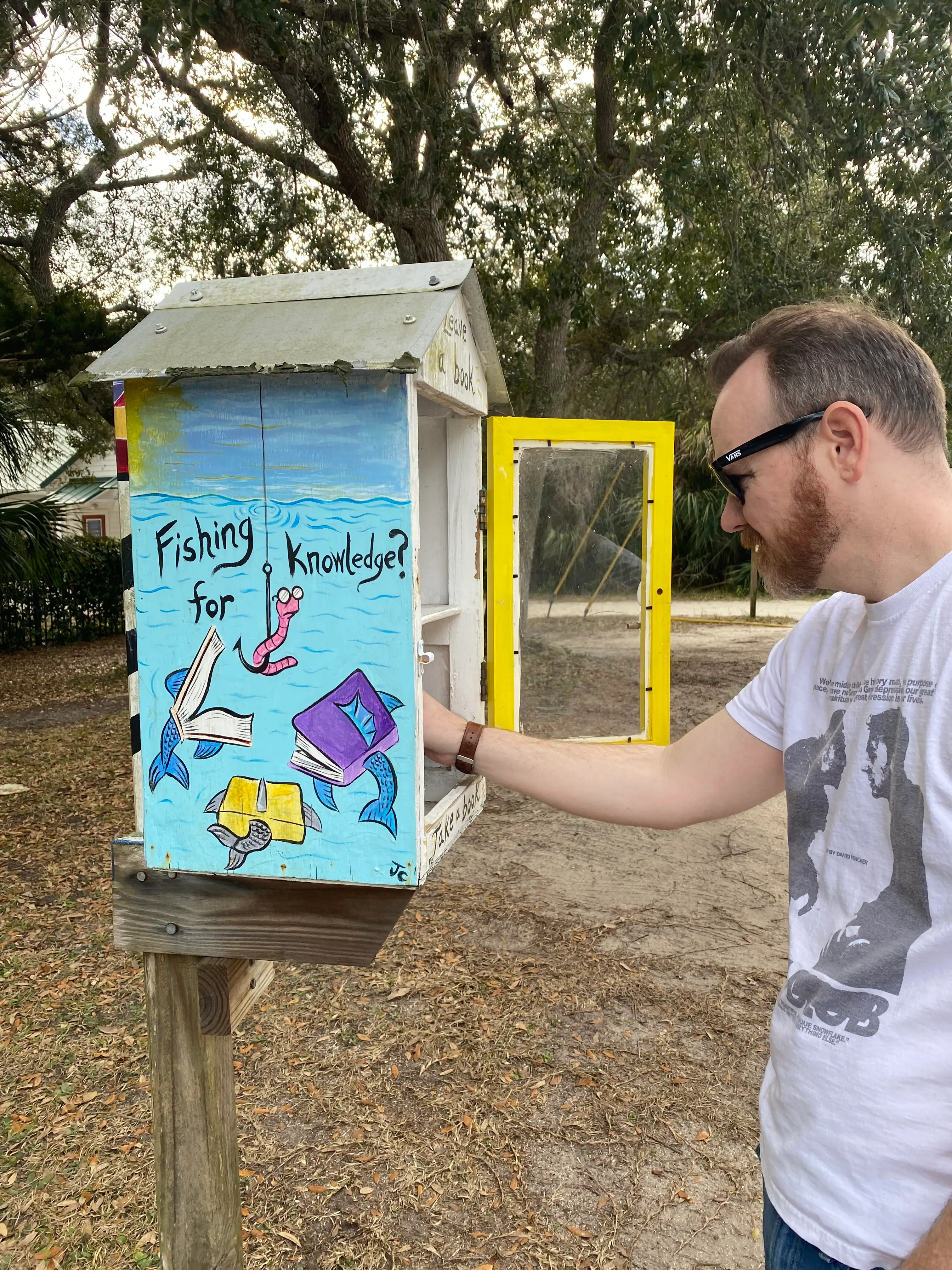The author's husband poses at a Little Free Library.
