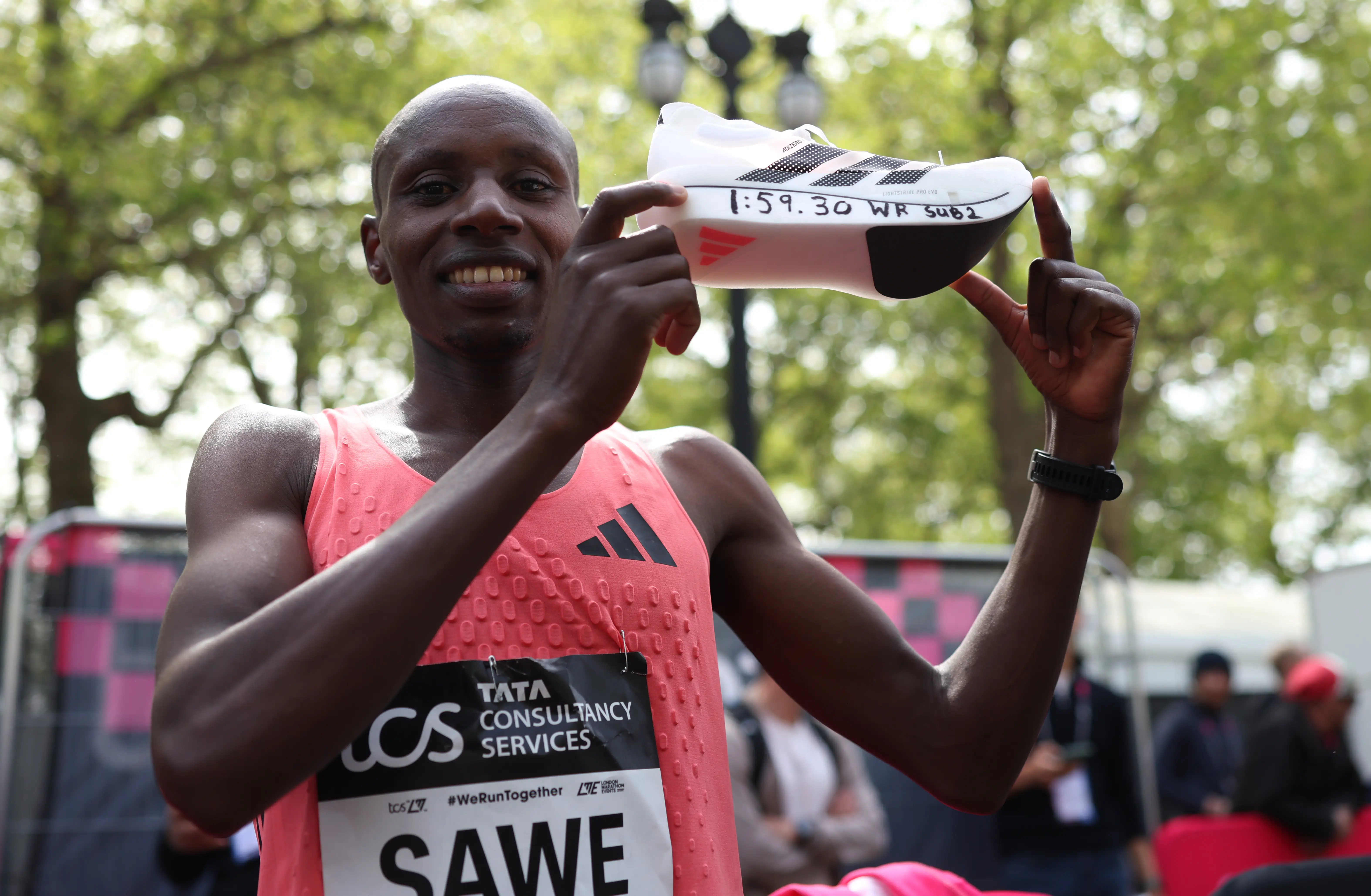 Sabastian Sawe holds up his Adidas shoe with the 1:59.30 world-record-winning time on it.