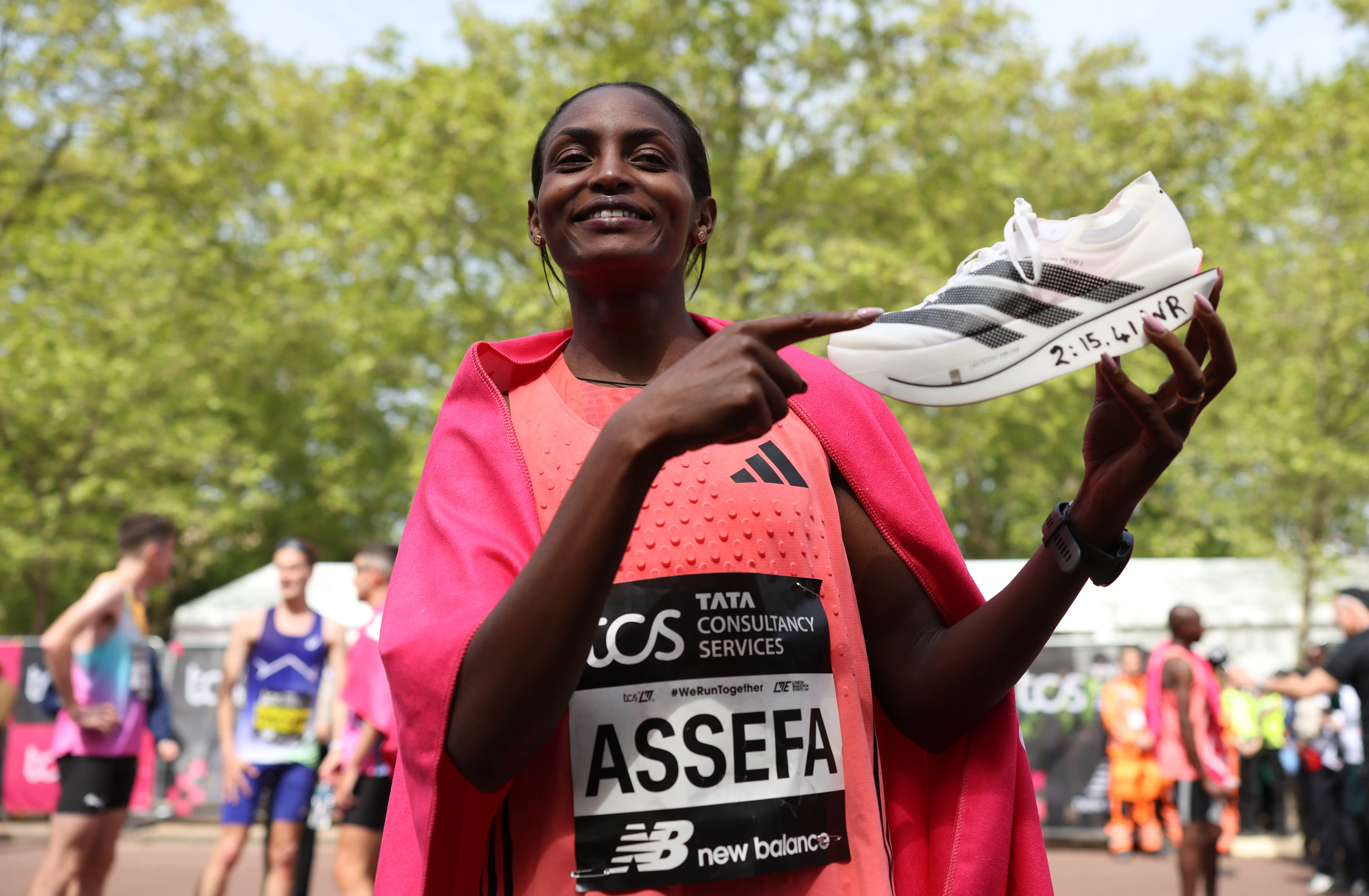 Tigst Assefa holds up the shoe she wore during her record-winning race at the 2026 London Marathon.