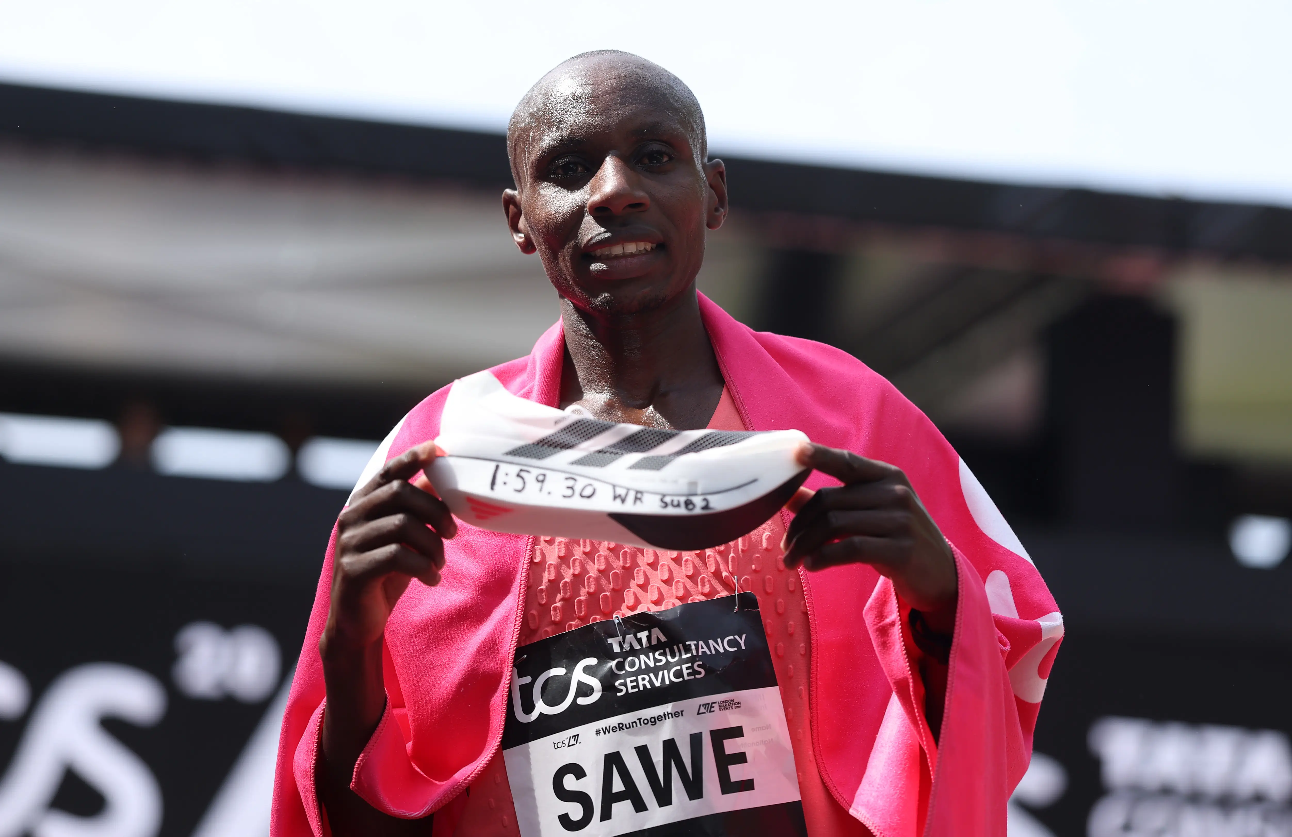 Sabastian Sawe holds up the Adidas shoe he wore after winning with a new world record time during the London Marathon.