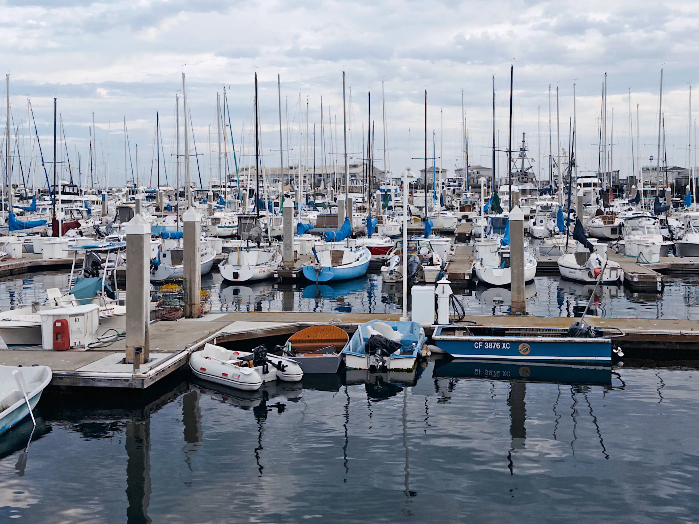 Boats docked at a crowded marina on a cloudy day.