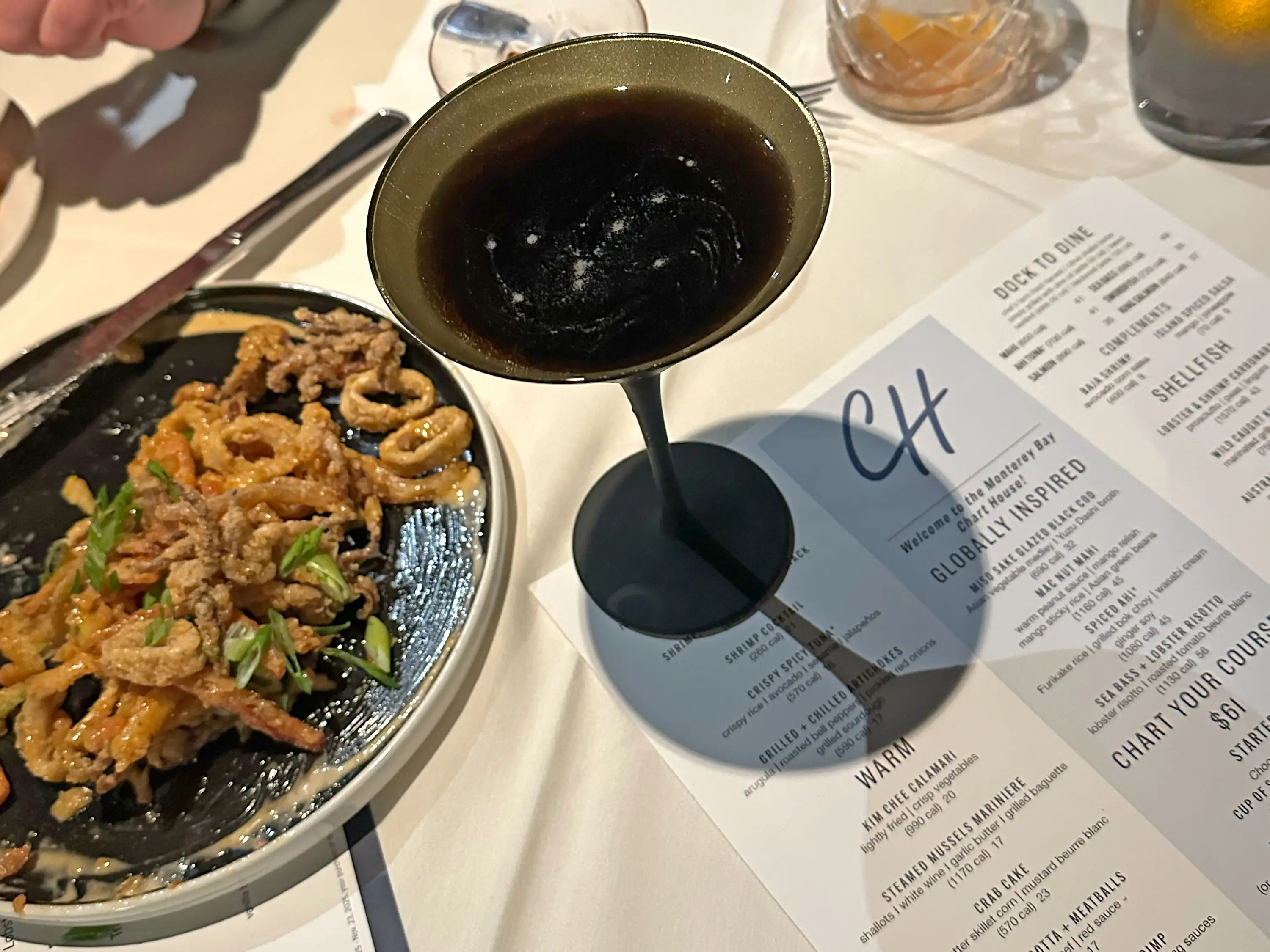 A plate of fried calamari and a cocktail on a table with a Chart House menu.