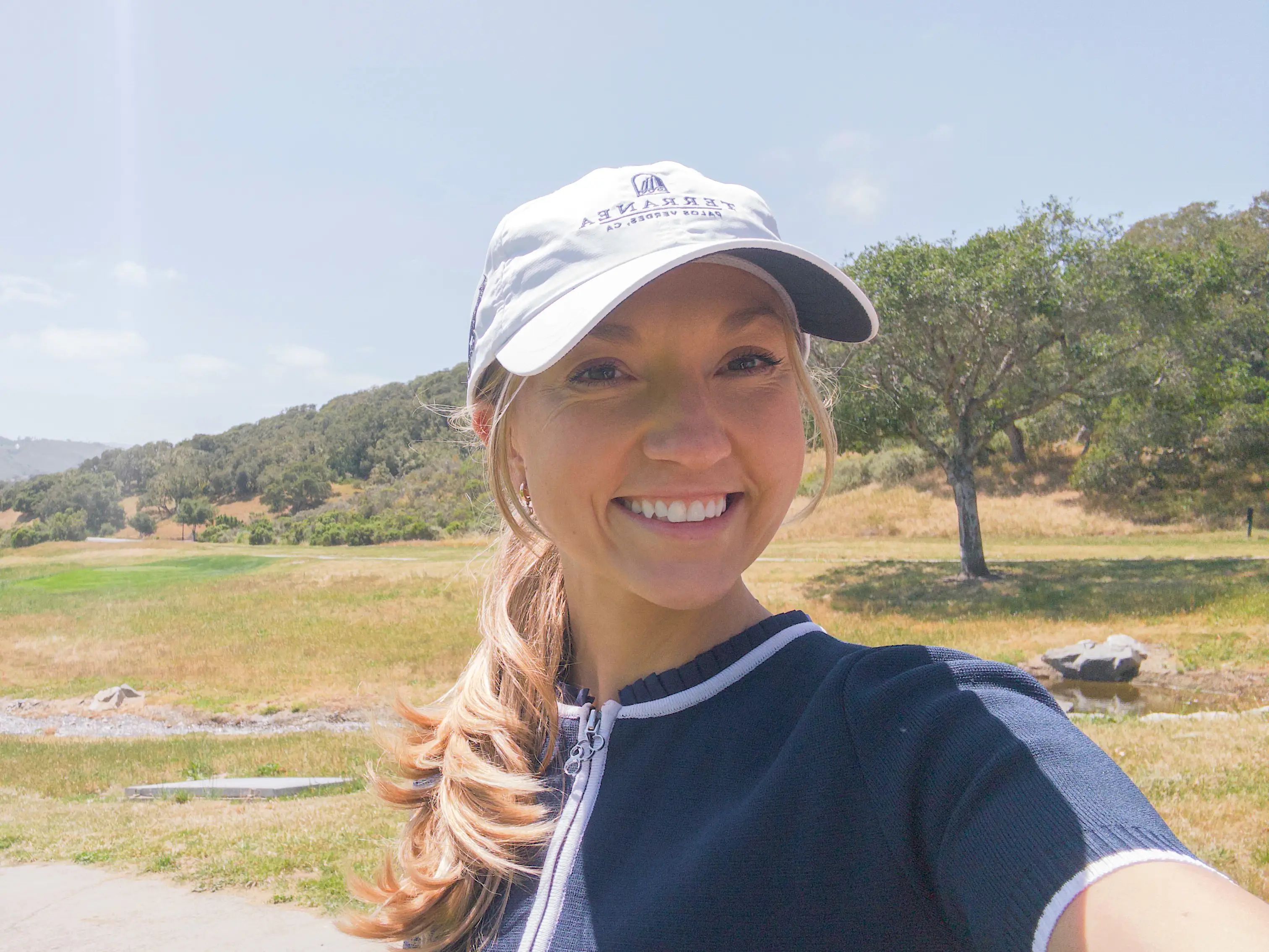 Chloe takes a selfie on a golf course on a sunny day.