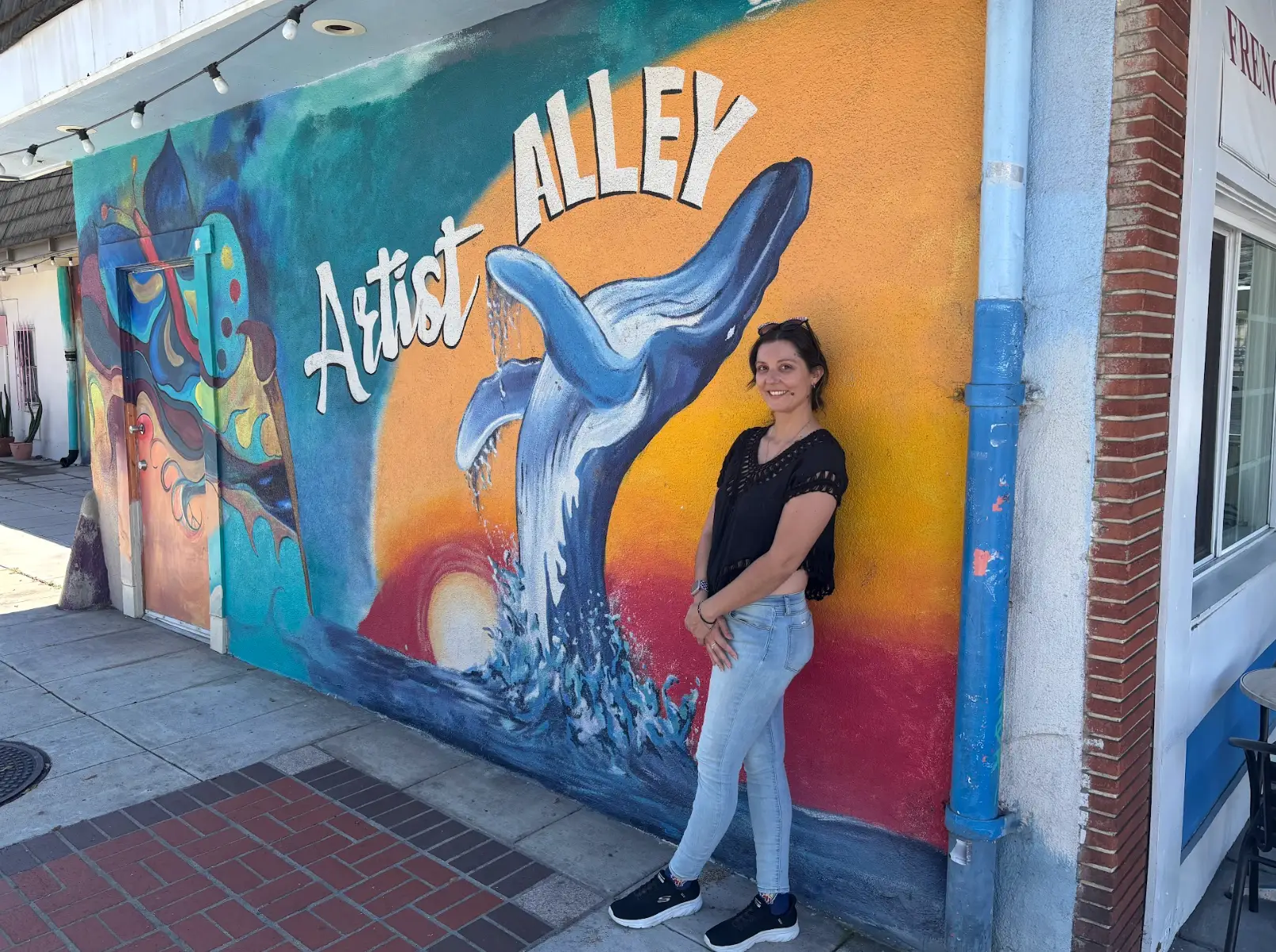 The writer standing in front of a colorful mural that says 