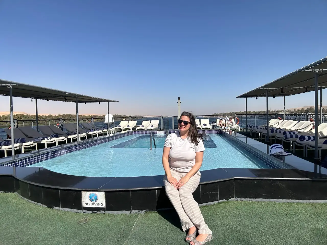Woman sitting by pool on rooftop deck
