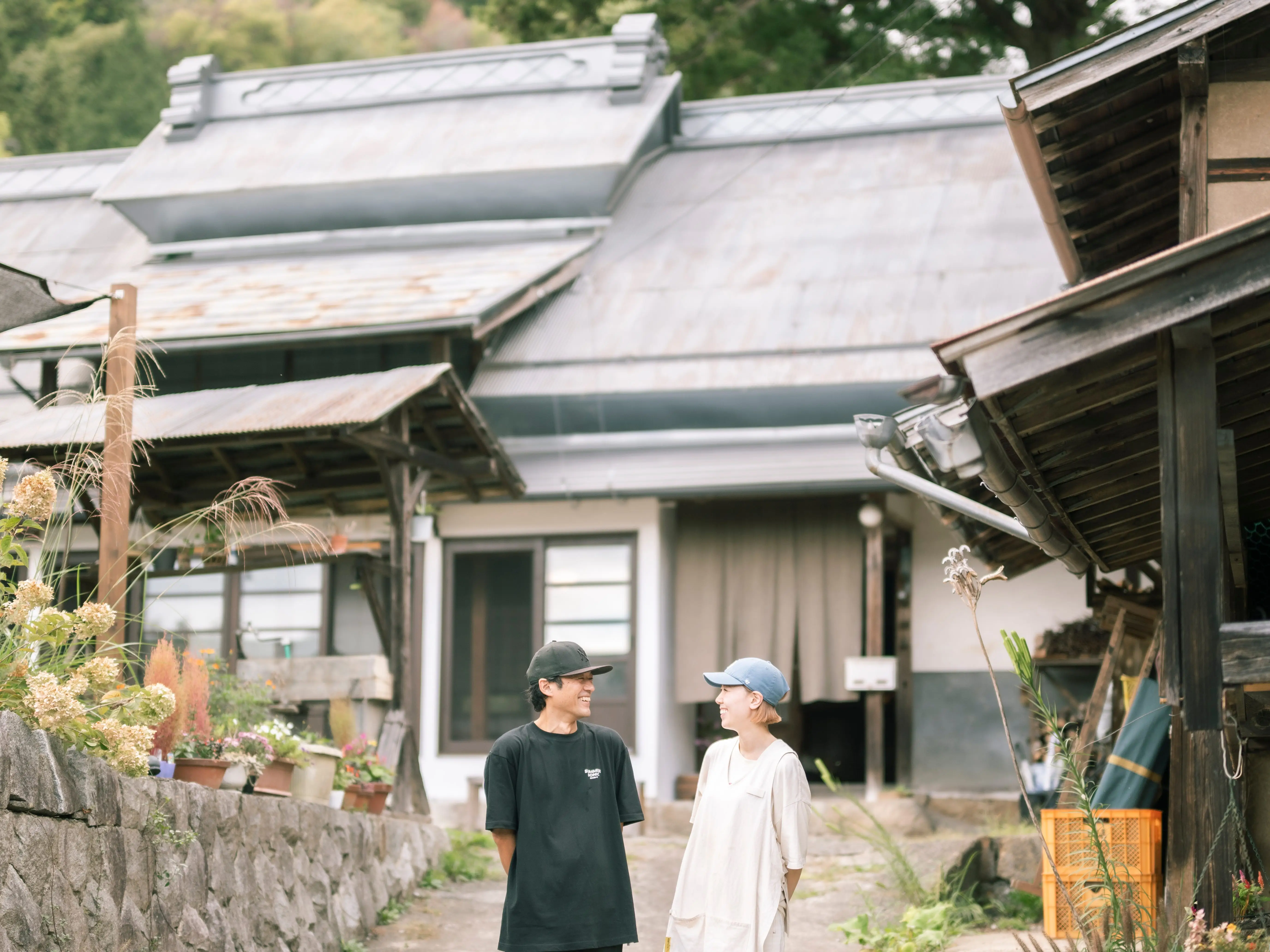 Husband and wife standing outside of tradiational house in Japan.