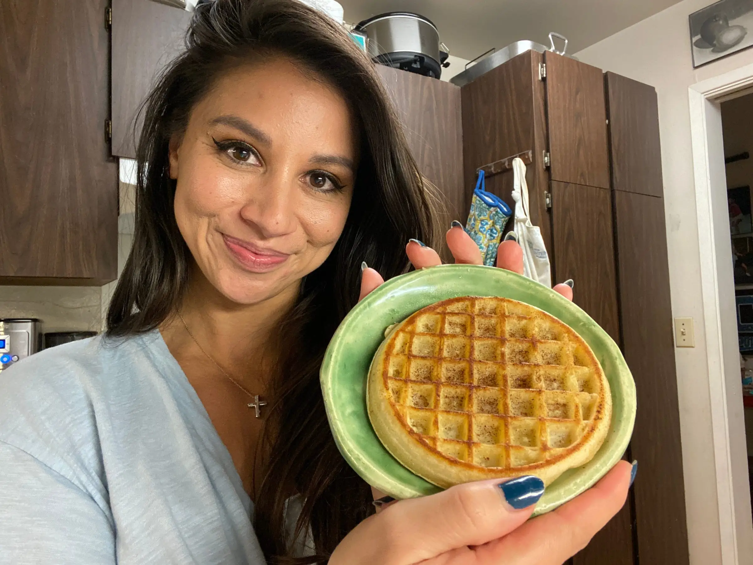 Woman smiling holding waffle on plate