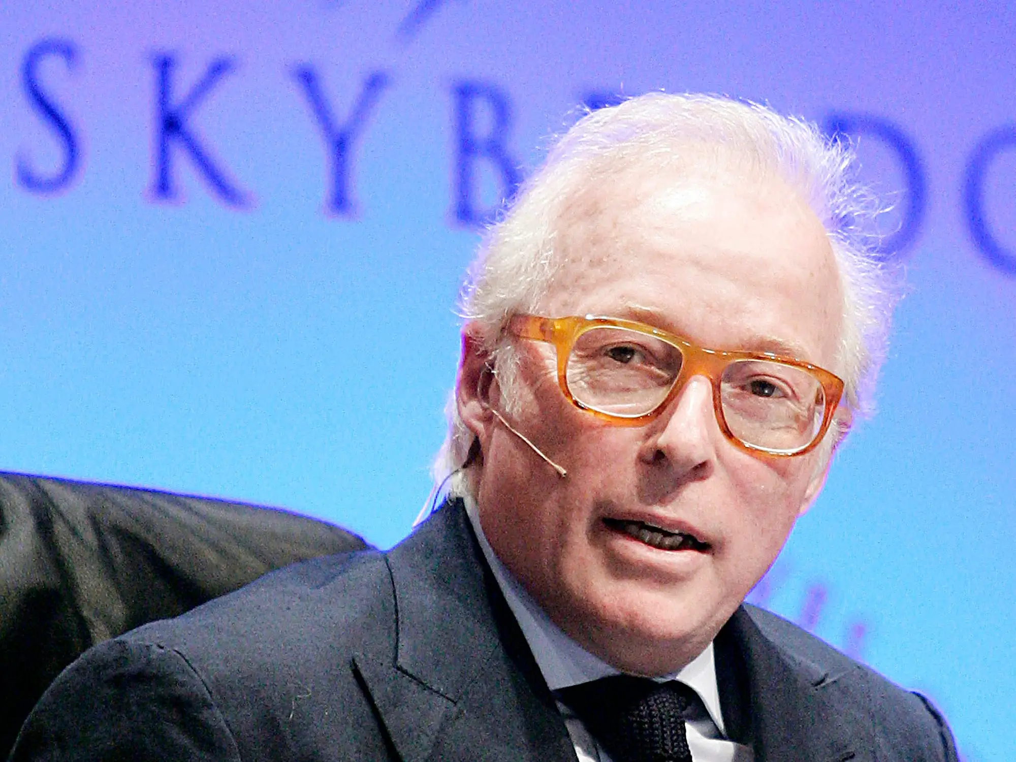 Izzy Englander speaks onstage in a dark suit