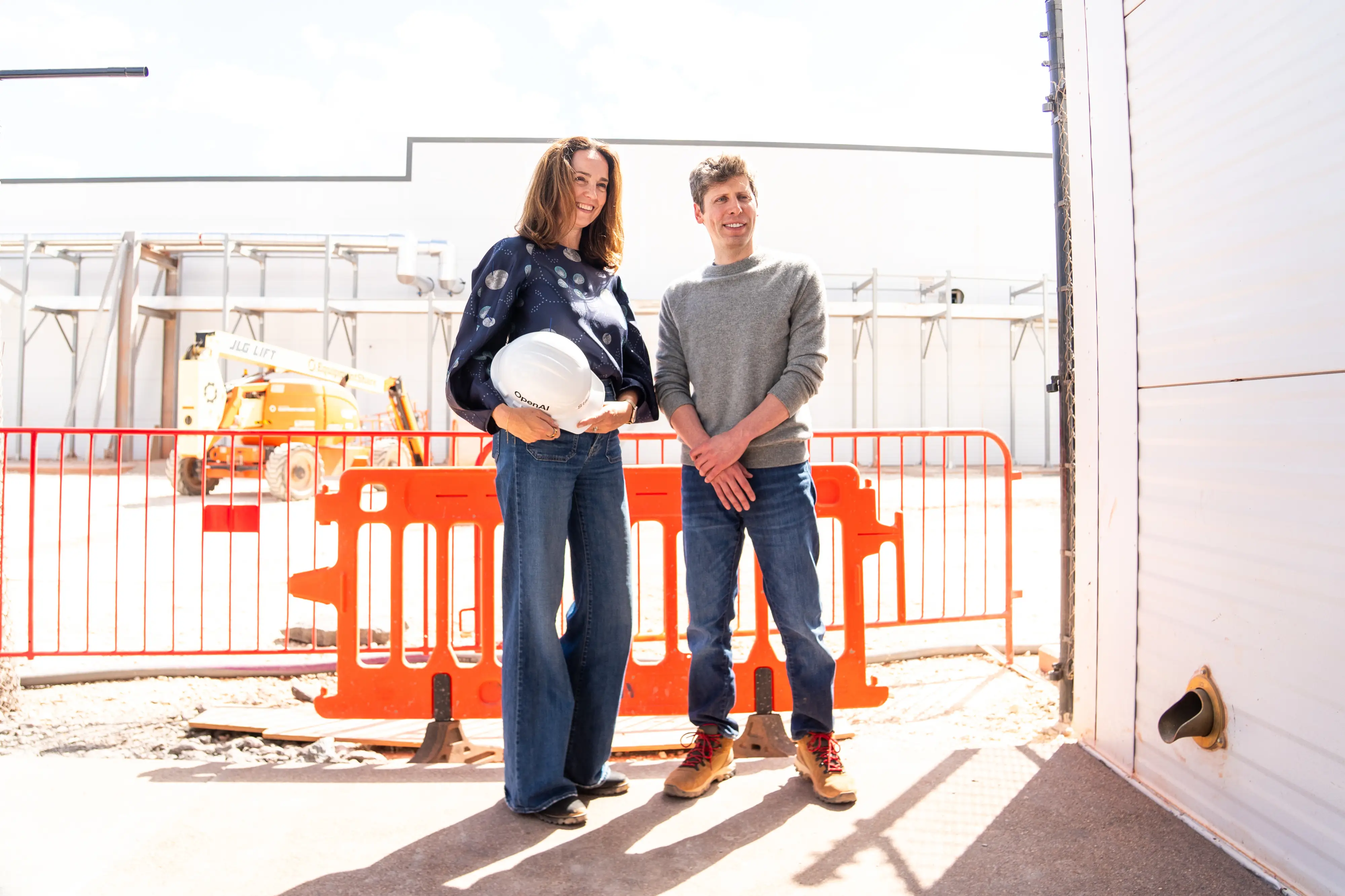 OpenAI's Sarah Friar and Sam Altman stand at a construction site.
