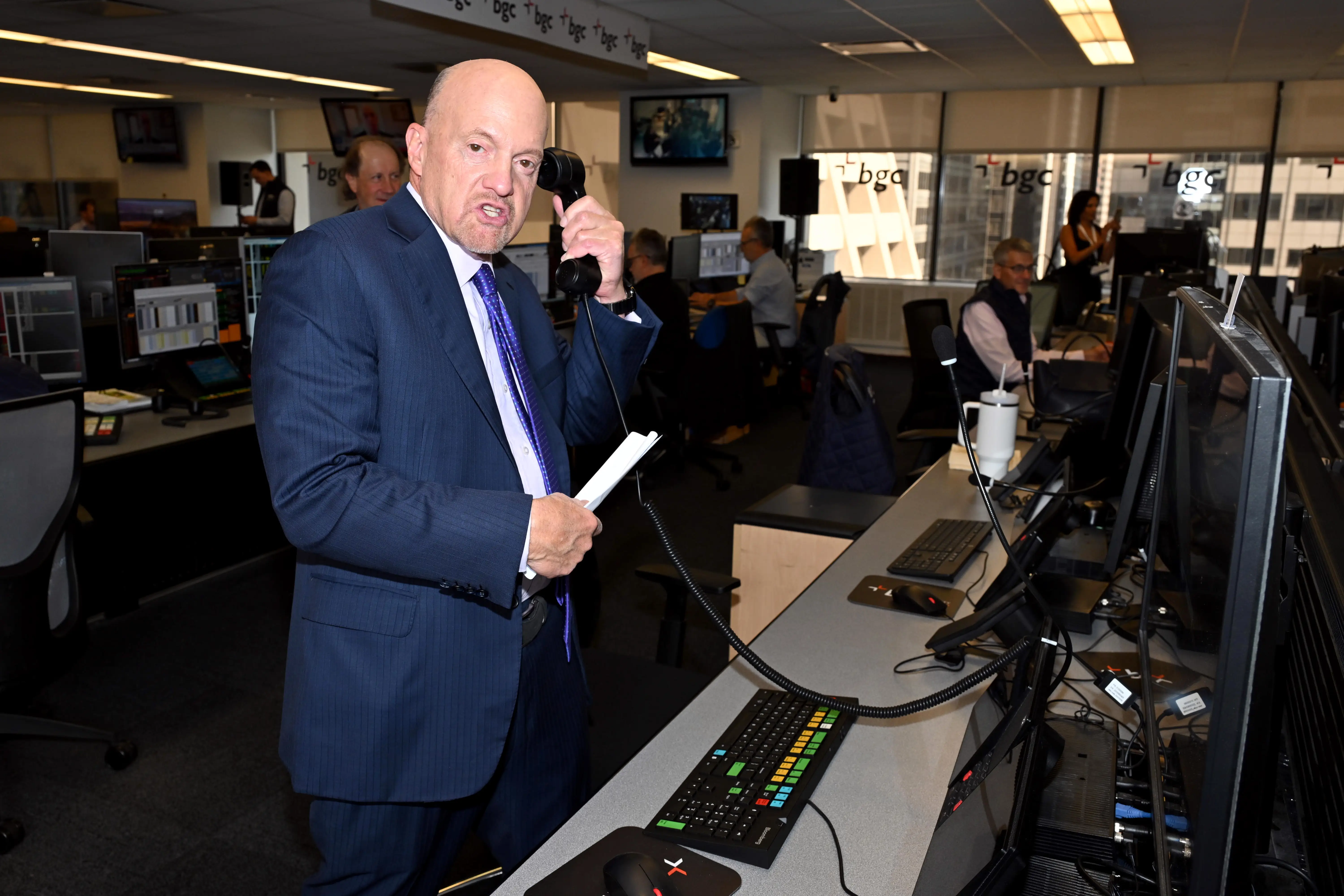 Jim Cramer is in a blue suit, holding a phone and looking at the camera.