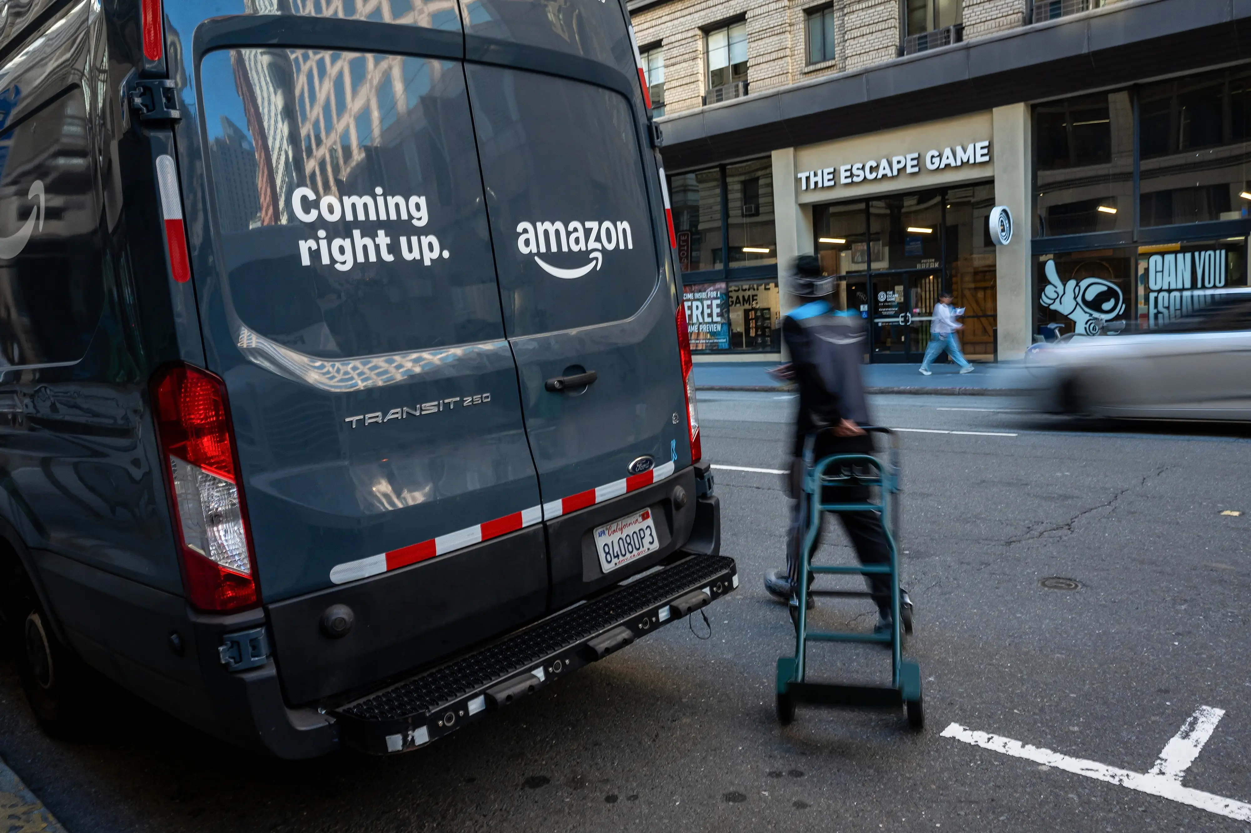 A worker pulls a handcart near an Amazon delivery in San Francisco