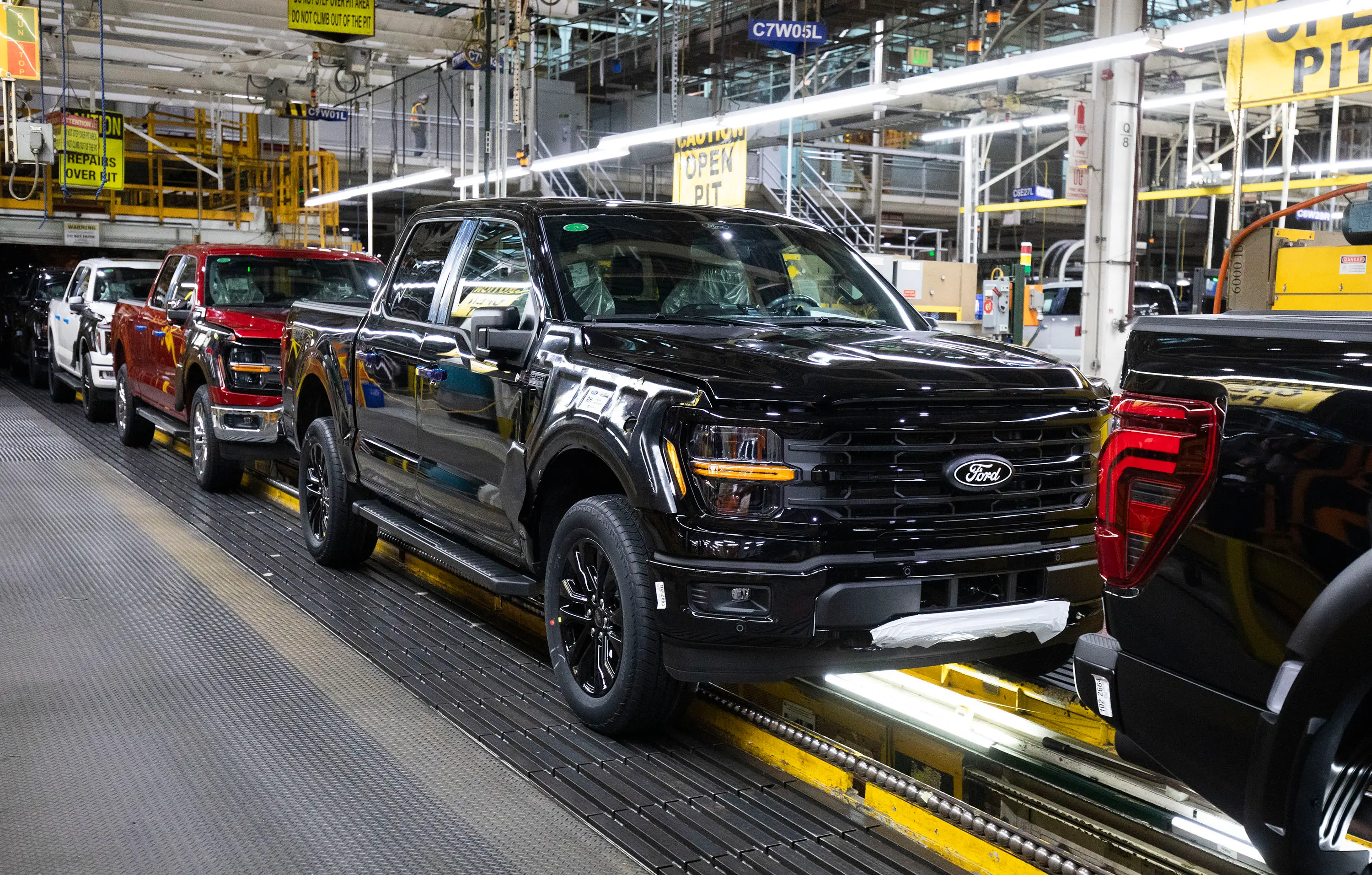 A production line carts Ford F-150 pickups through a factory.