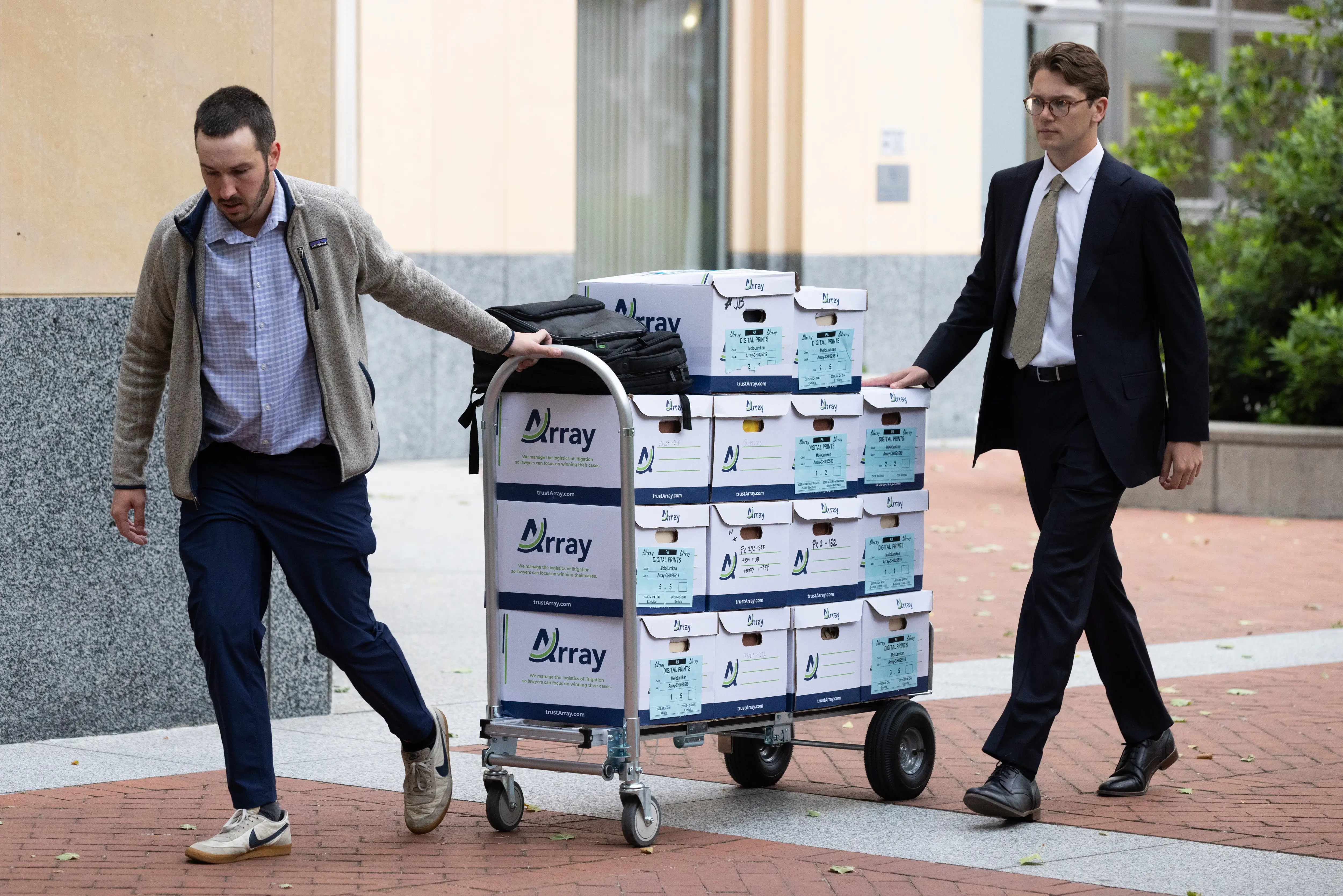 Two men wheel a dolly filled with boxes.