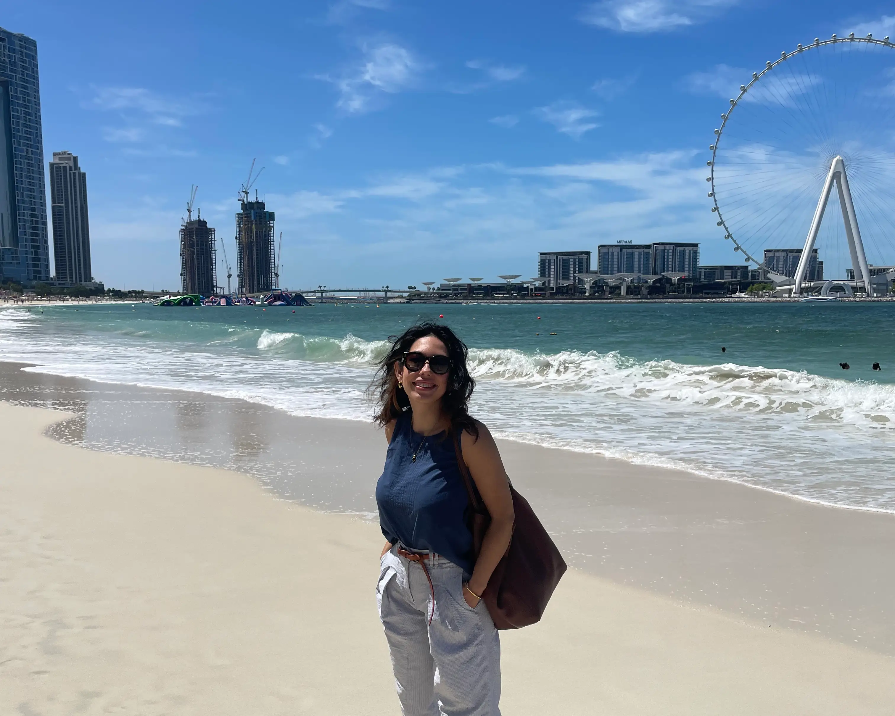 A woman posing on the beach with Dubai in the background.