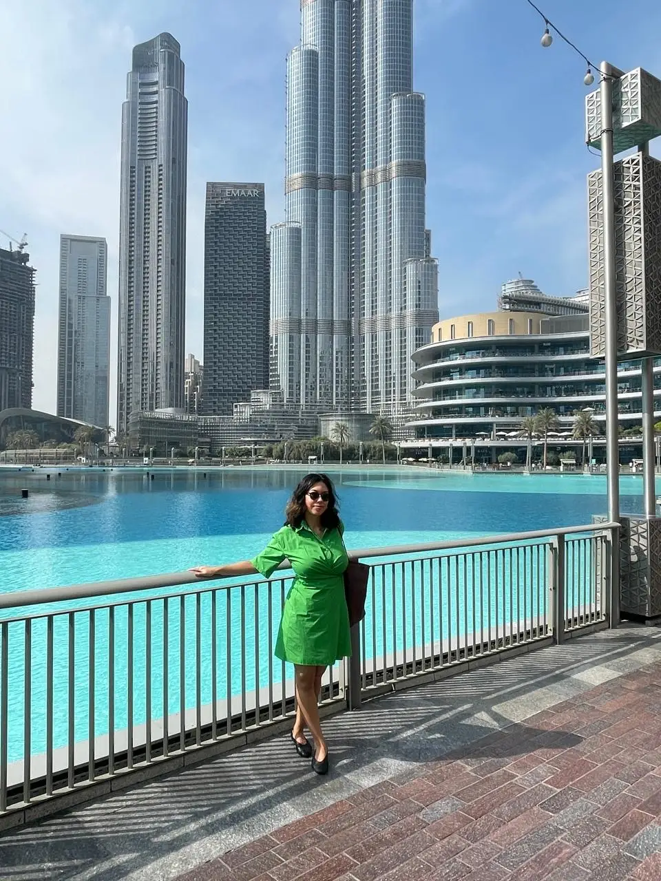 A woman in a green dress posing by the Dubai Mall.