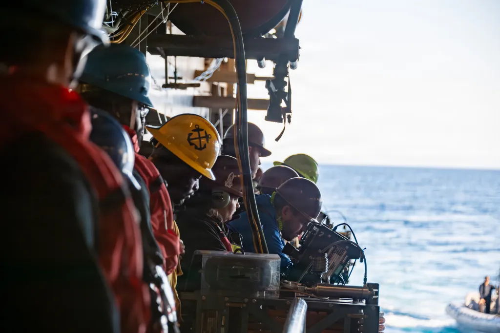 Crew members in hard hats and safety vests conduct recovery tests aboard the John P. Murtha.