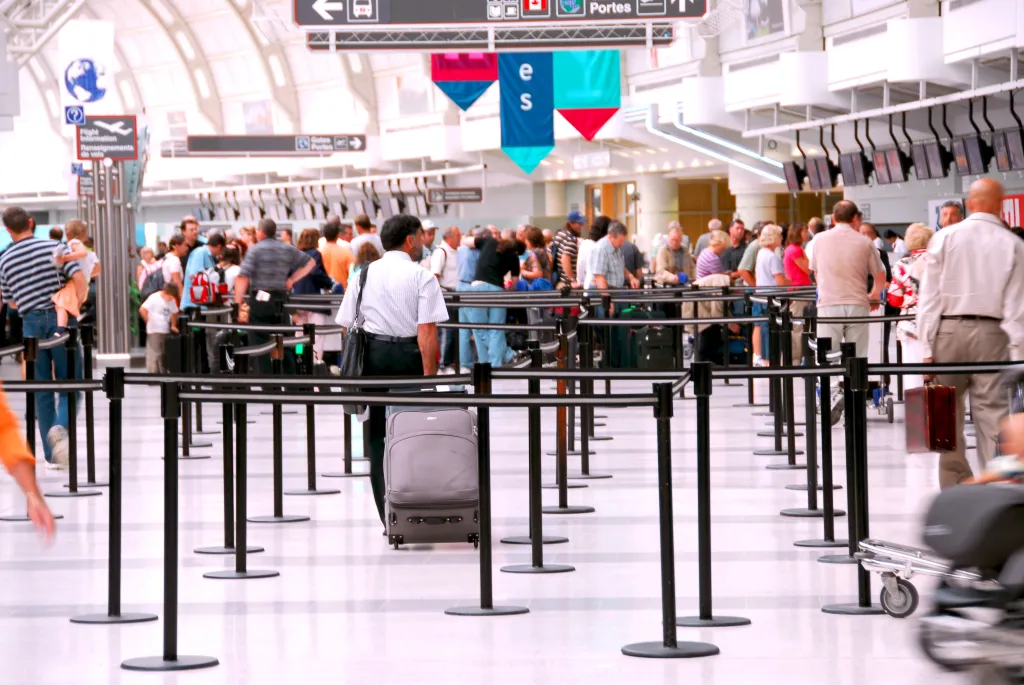 A crowd of people in an airport waiting in line.