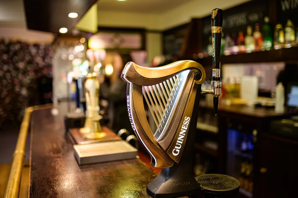 Guinness Harp beer dispenser on a bar counter.