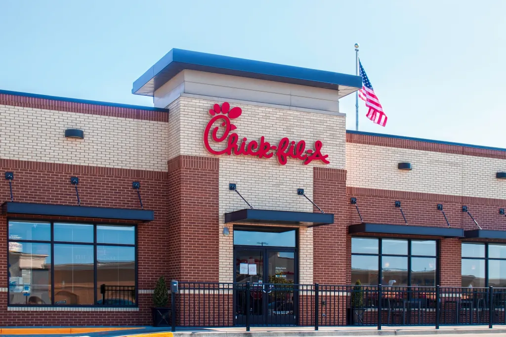 A Chick-fil-A store with an American flag flying above the building.