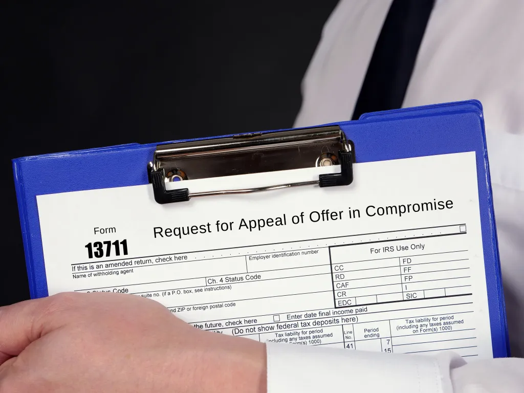 Form 13711 Request for Appeal of Offer in Compromise held on a blue clipboard.