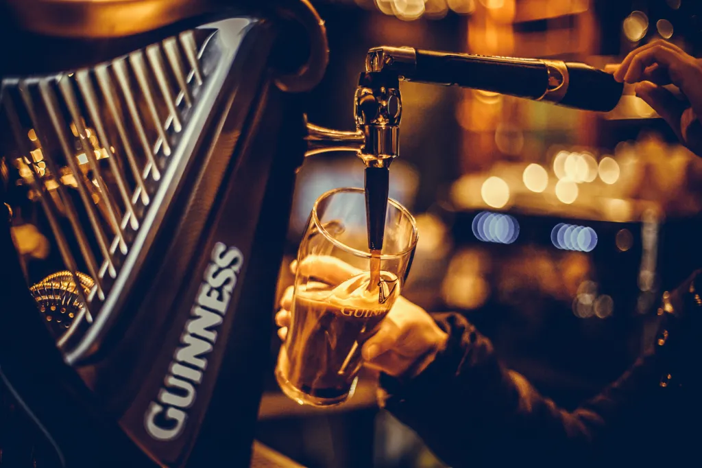 Bartender pouring a pint of Guinness beer in a pub.
