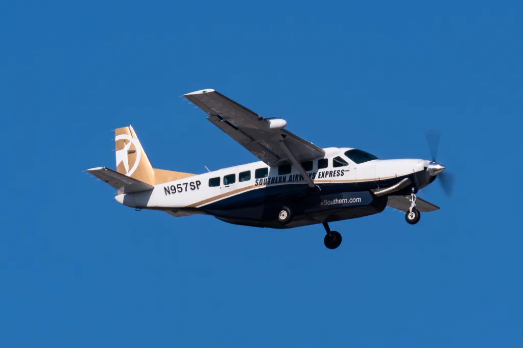 A Southern Airways Express Cessna 208B N957SP propeller plane flying against a clear blue sky.