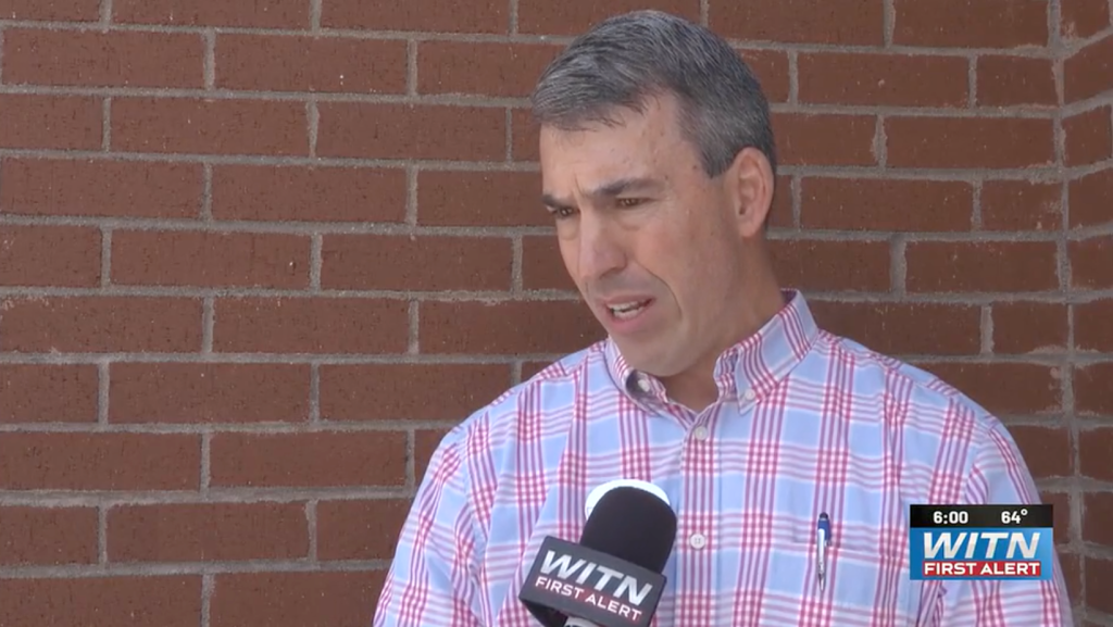 Man in a blue and pink plaid shirt speaking into a WITN First Alert microphone.