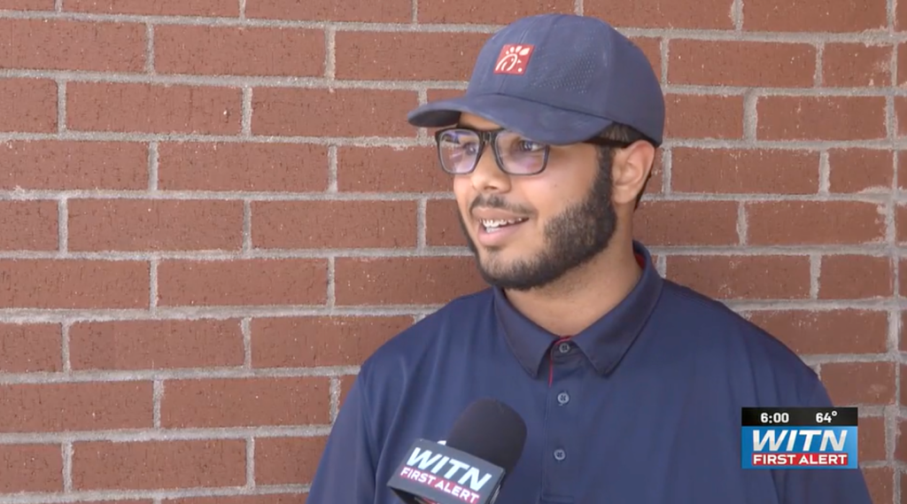 A man in a Chick-fil-A uniform speaks into a WITN microphone.