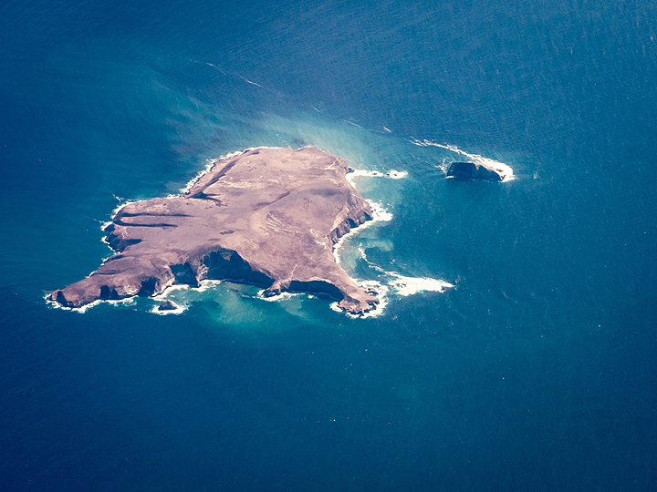 Aerial view of a remote island surrounded by deep blue water.